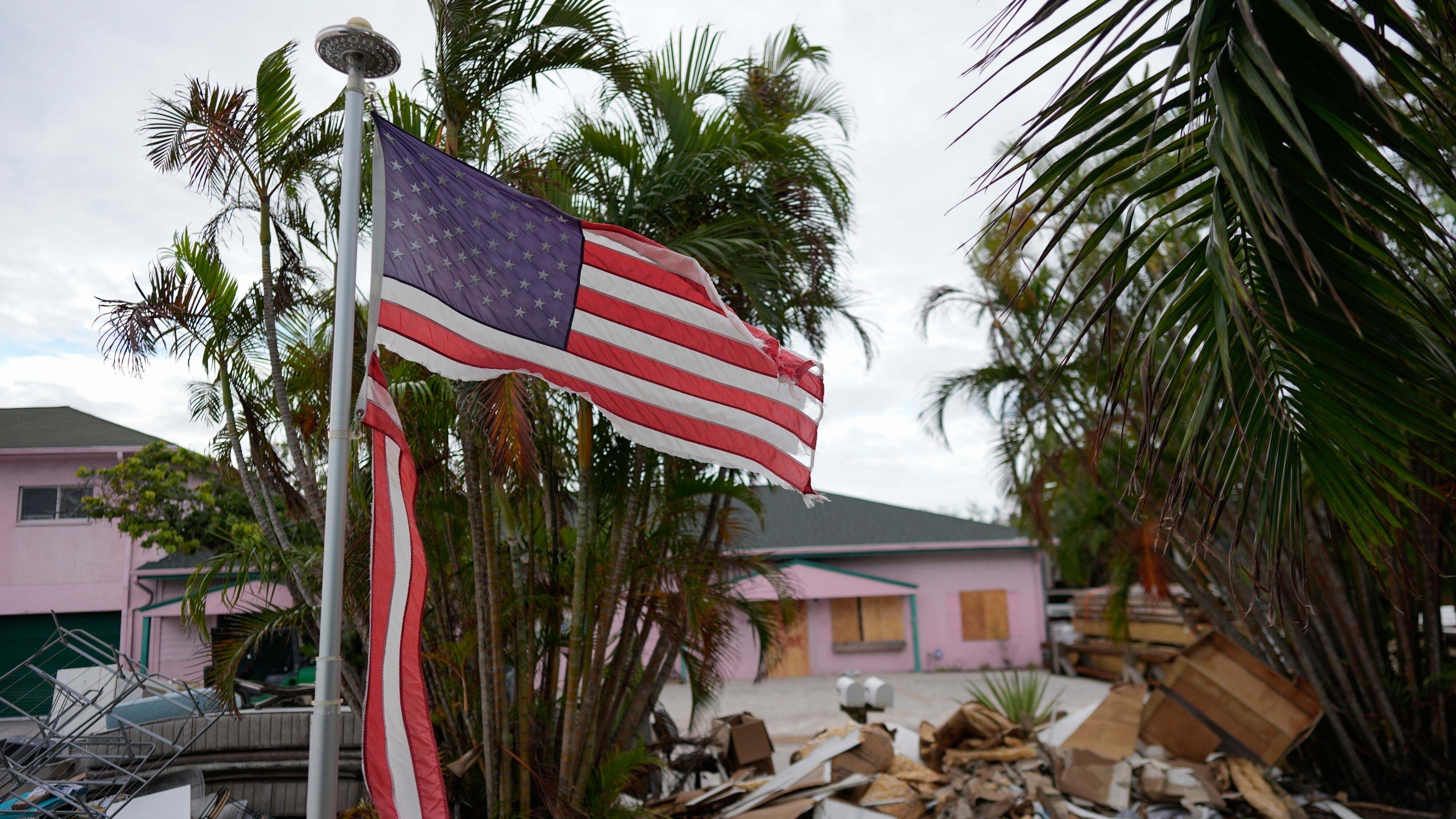 ARCHIVO - Una bandera americana desgarrada ondea fuera de una casa con muebles y enseres domésticos dañados por el huracán Helene apilados en el exterior, a lo largo de la calle a la espera de ser recogidos antes de la llegada del huracán Milton en Holmes Beach en Anna Maria Island, Florida, el 8 de octubre de 2024. (Foto AP/Rebecca Blackwell, Archivo)