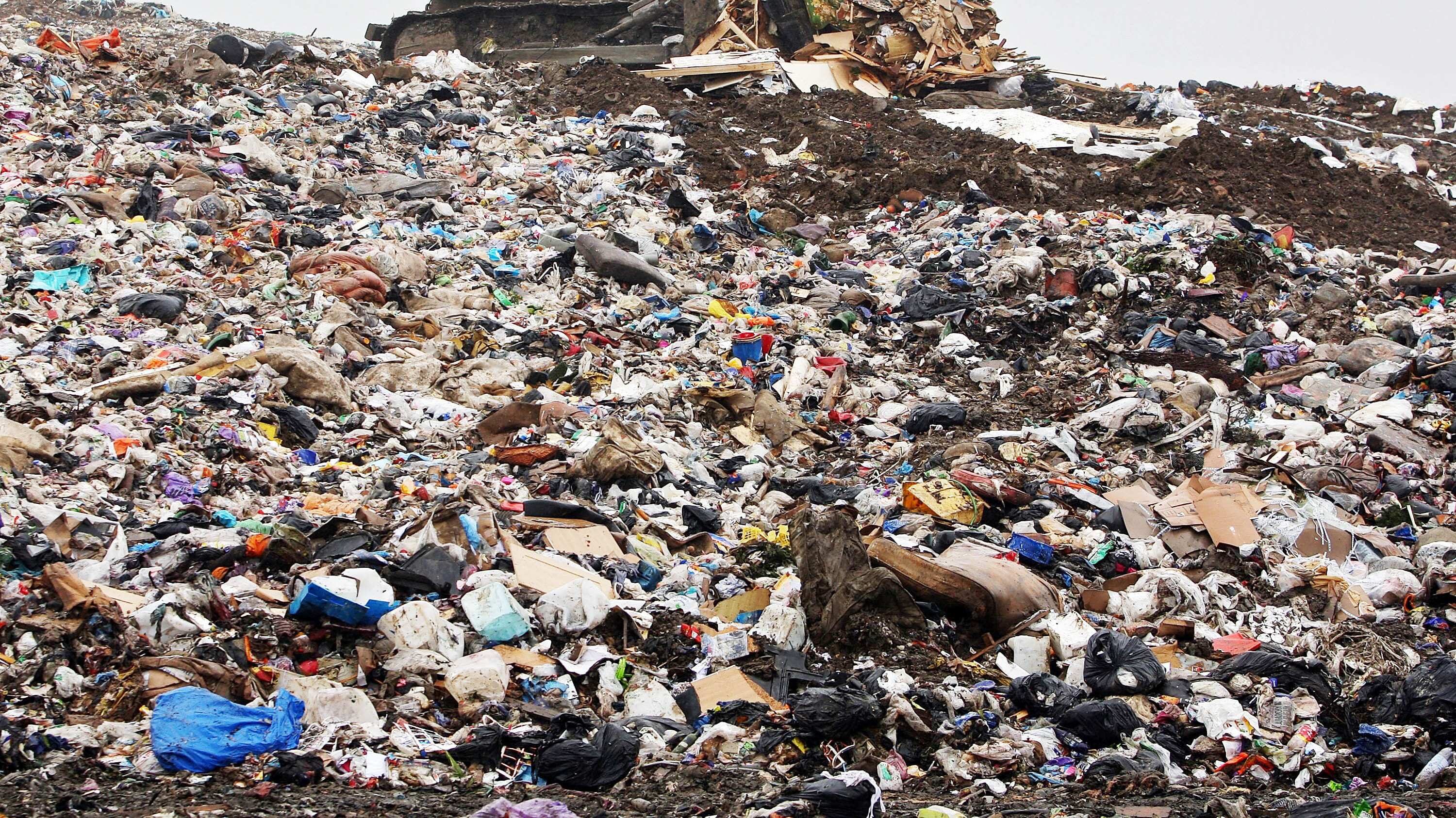 Una excavadora mueve basura en un vertedero.