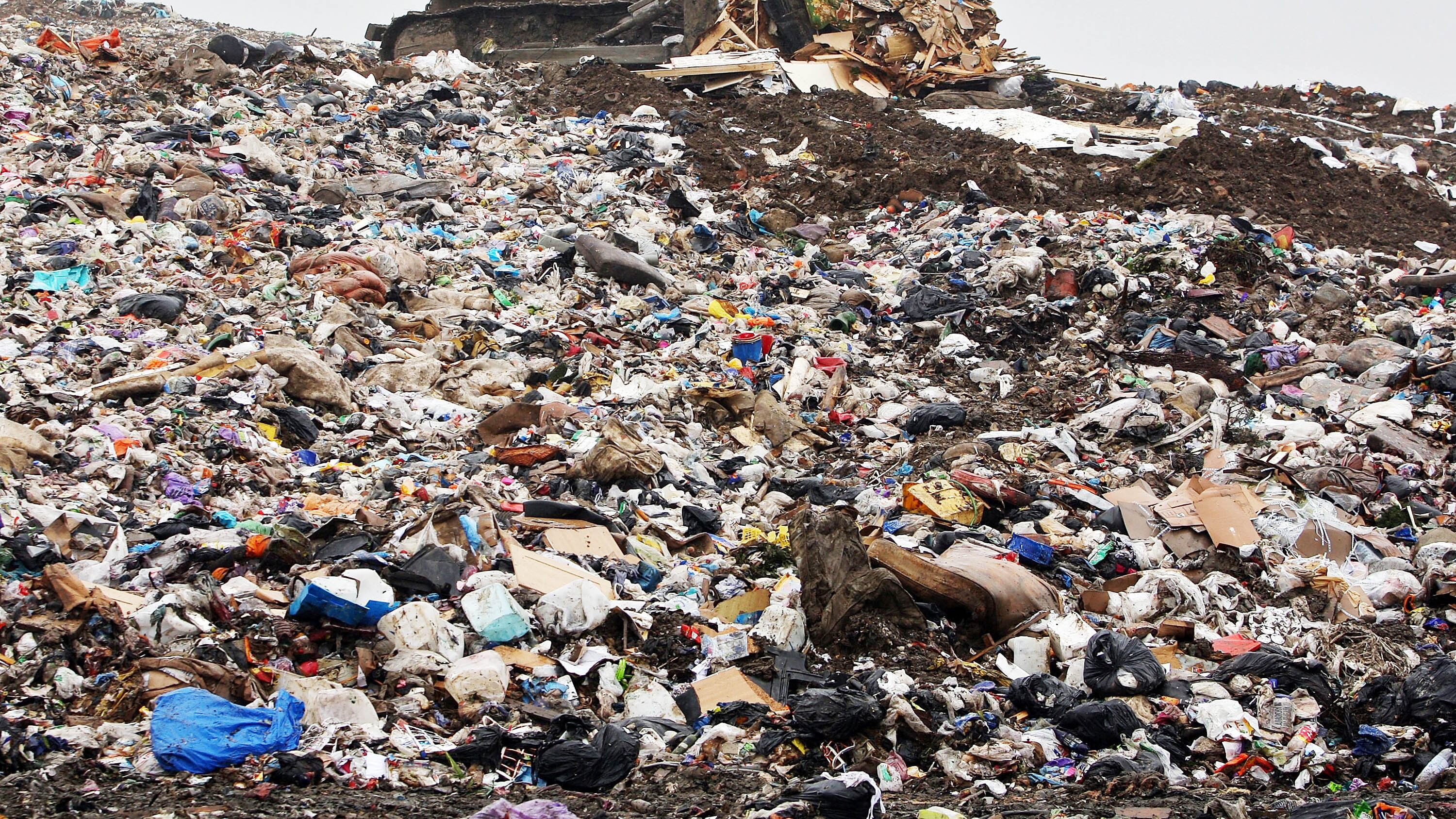 Una excavadora mueve basura en un vertedero.