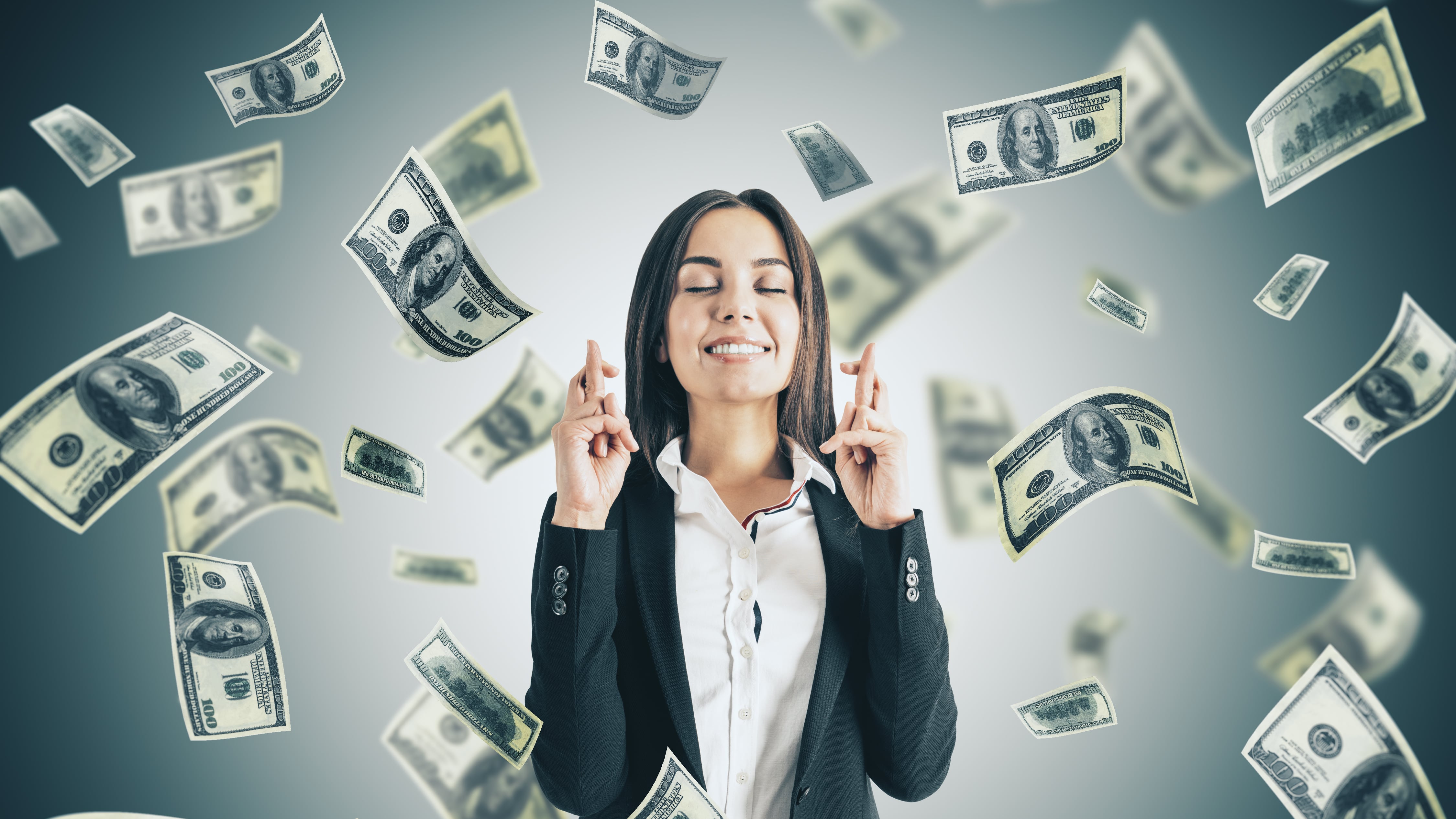 Empresaria cruzó los dedos en busca de suerte y caída del billete de un dólar sobre fondo gris.