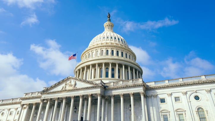 United States Capitol building with American flag over blue sky background, Washington DC