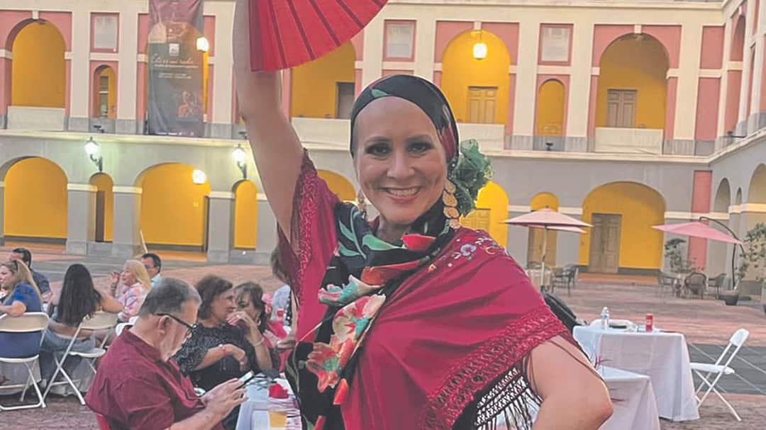 Elsa Victoria Lavergne Beauchamp, sobreviviente de cáncer de seno, posa y sonríe con un vestido flamenco.