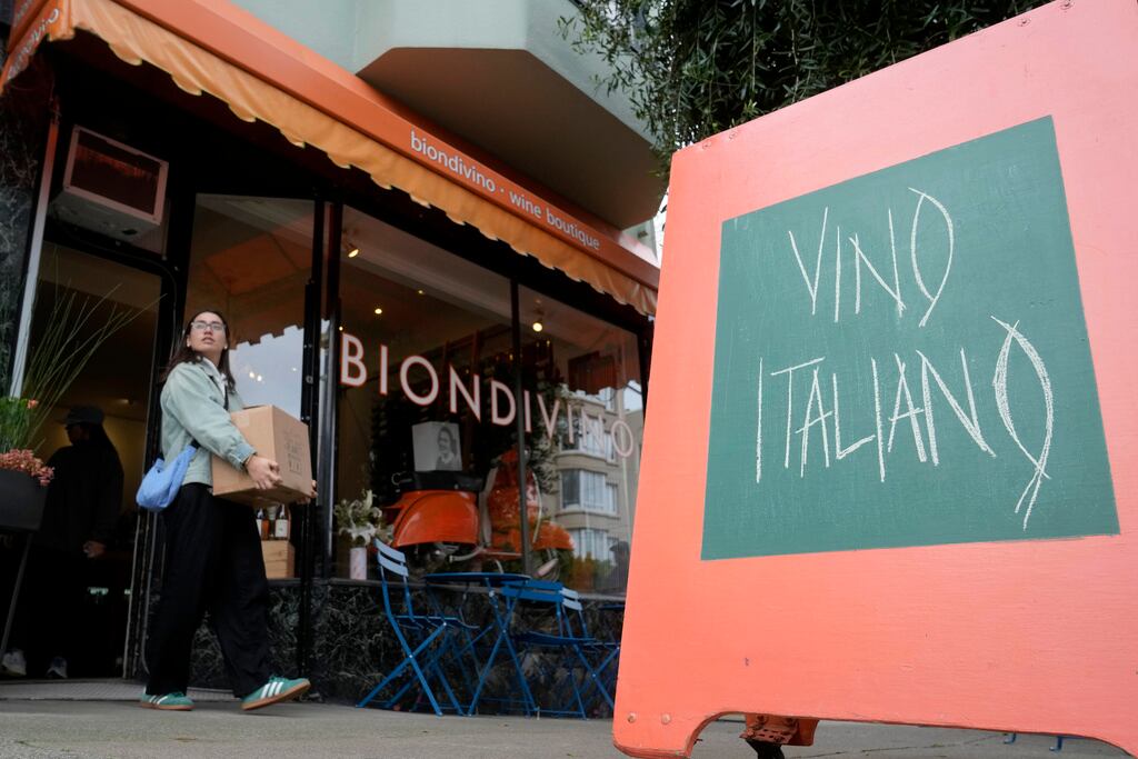 Courtney Scheetz lleva botellas de vino italiano después de comprar en la tienda de vinos Biondivino en San Francisco, el viernes 14 de marzo de 2025. (Foto AP/Jeff Chiu)