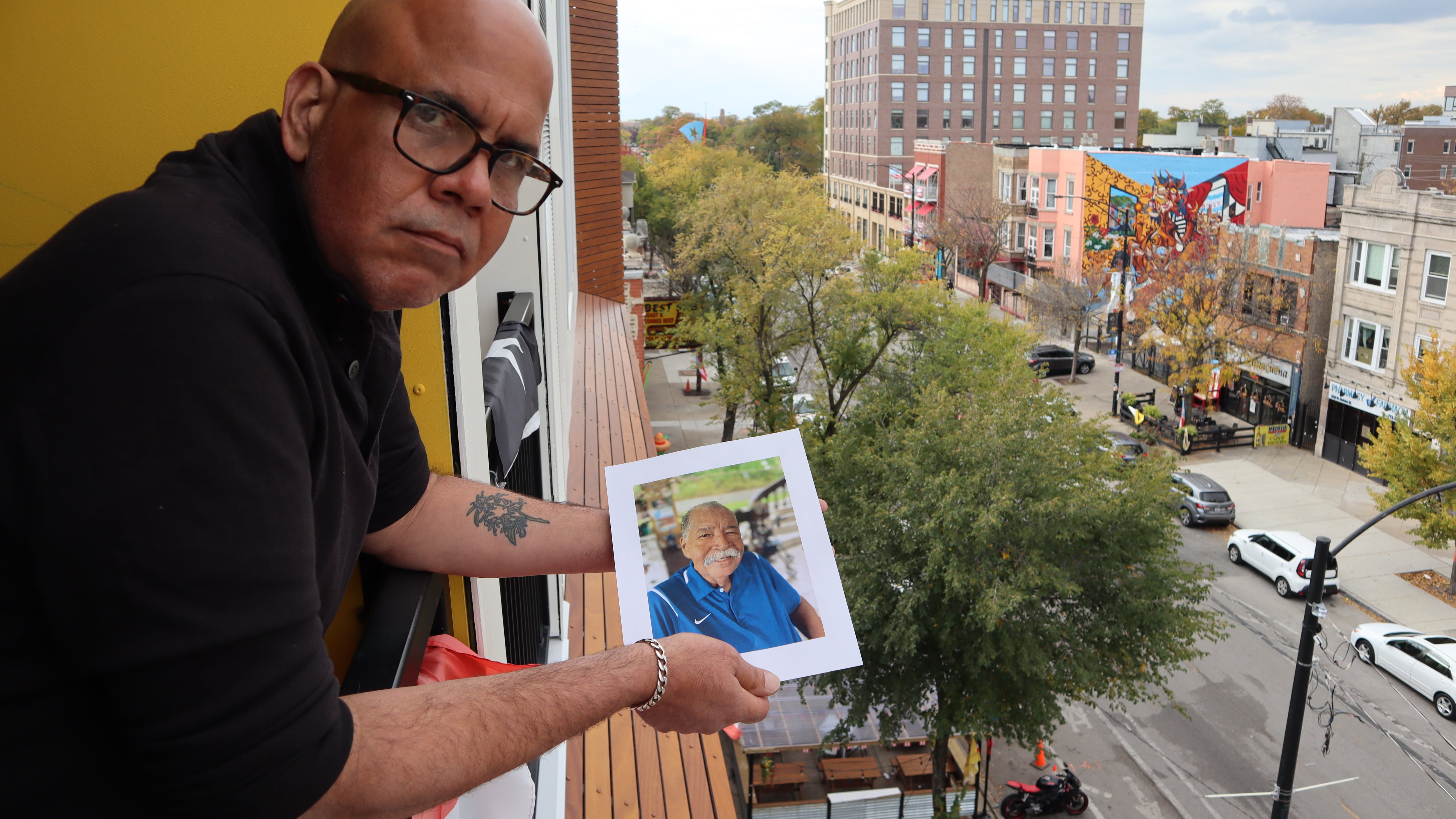 Elías Carmona Rivera sostiene la foto de su padre, Elías Carmona Alejandro, en el balcón de su apartamento en el barrio puertorriqueño de Chicago. Elías y su hermana Sandra son un ejemplo de los retos que enfrentan muchos hijos a cargo de cuidar a sus padres envejecidos, tanto en Puerto Rico como desde la diáspora.