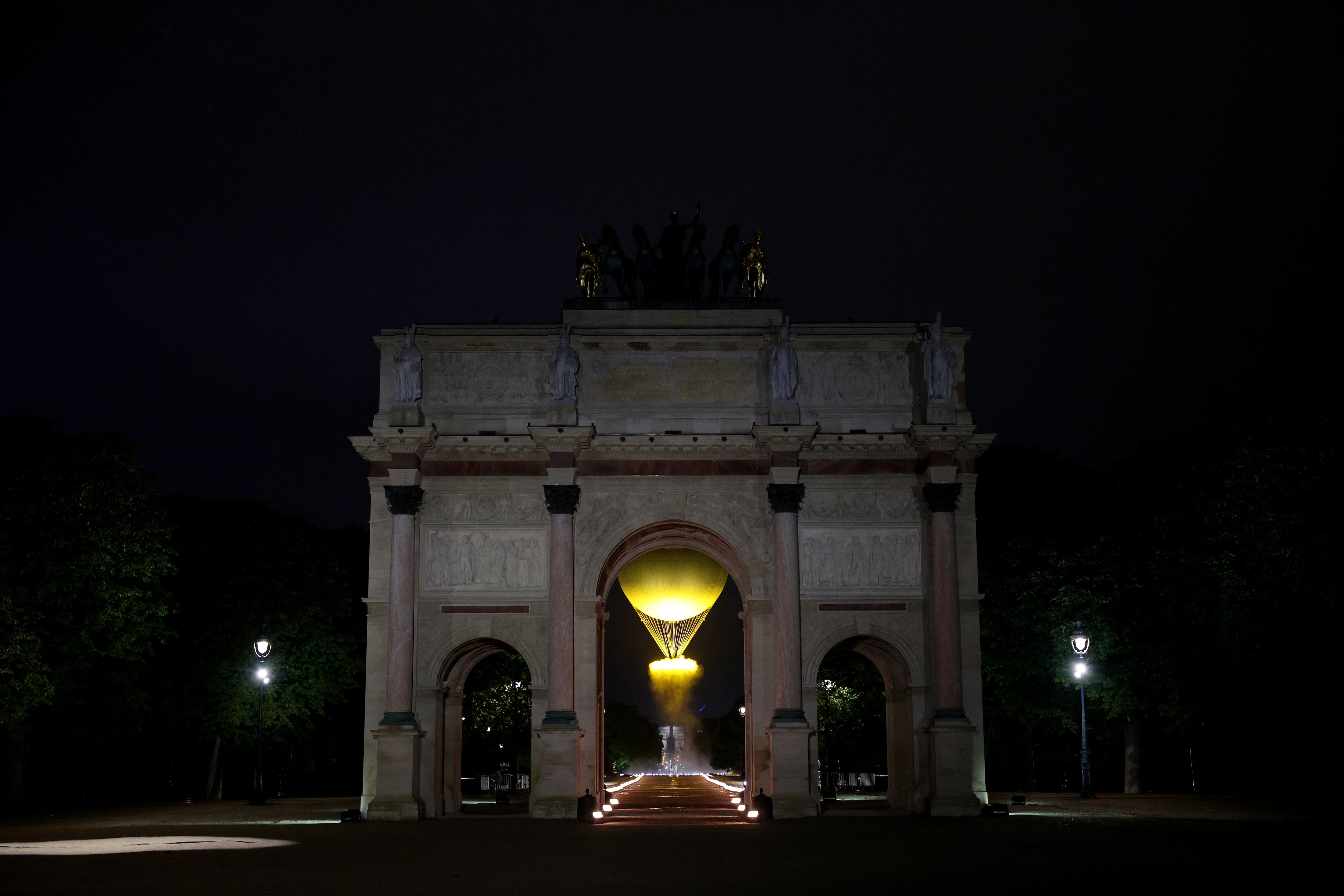 PARIS, FRANCE - JULY 26: A general view of through the Arc de Triomphe du Carrousel as Torch bearers French Athlete Marie-Jose Perec and French Judo Practitioner Teddy Riner (obscured) look on as the Olympic Cauldron lifts into the sky after being lit at the Gardens of the Tuileries during the opening ceremony of the Olympic Games Paris 2024 on July 26, 2024 in Paris, France. (Photo by Adam Pretty/Getty Images)