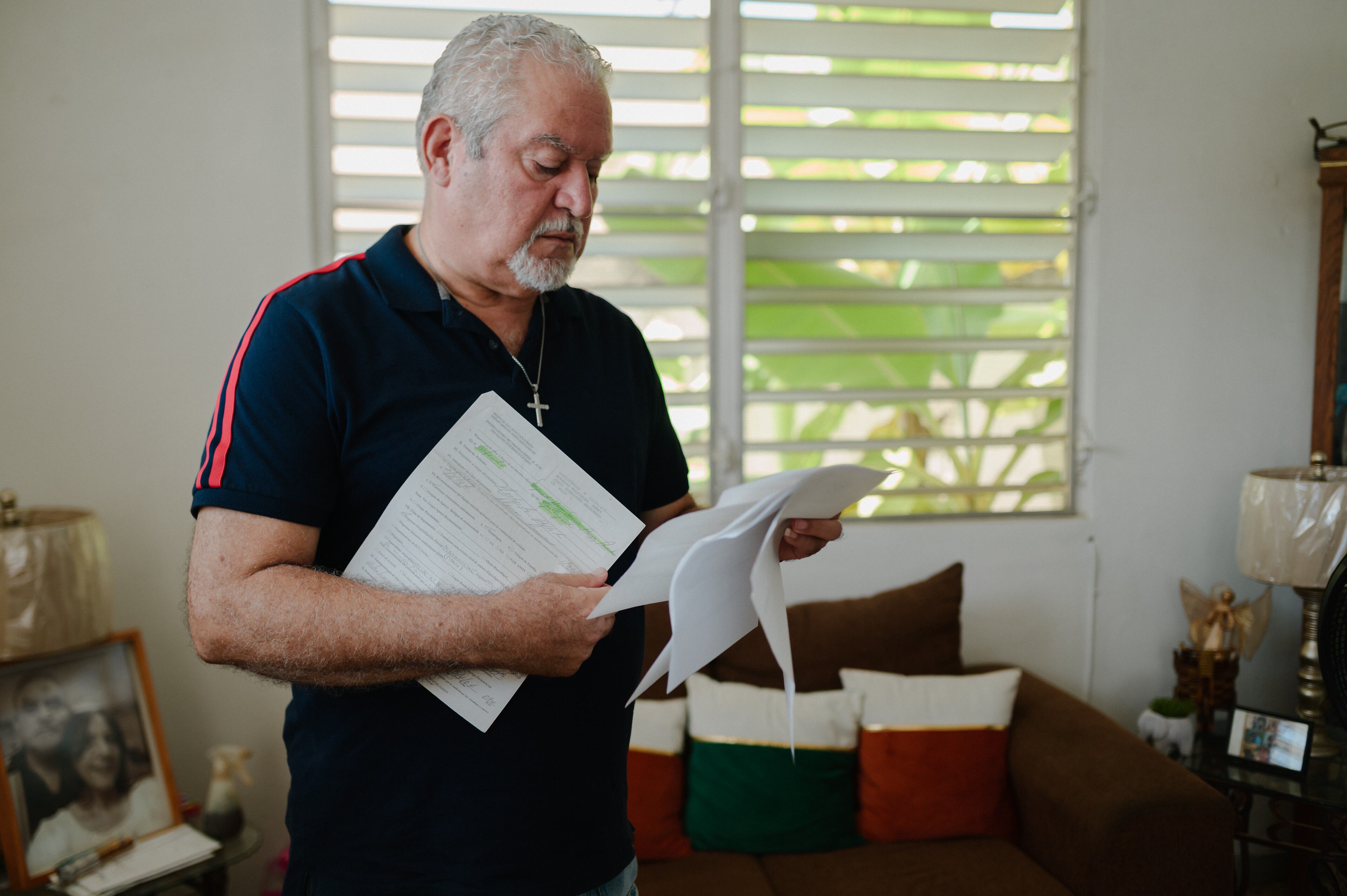 22 de julio de 2024. Salinas, PR. Retrato del exempleado afectado Henry Morales en la sala de su casa en Hacienda La Margarita. En al foto, Henry está revisando sus documentos médicos. (Foto por Esteban G. Morales Neris | Centro de Periodismo Investigativo/Grist)