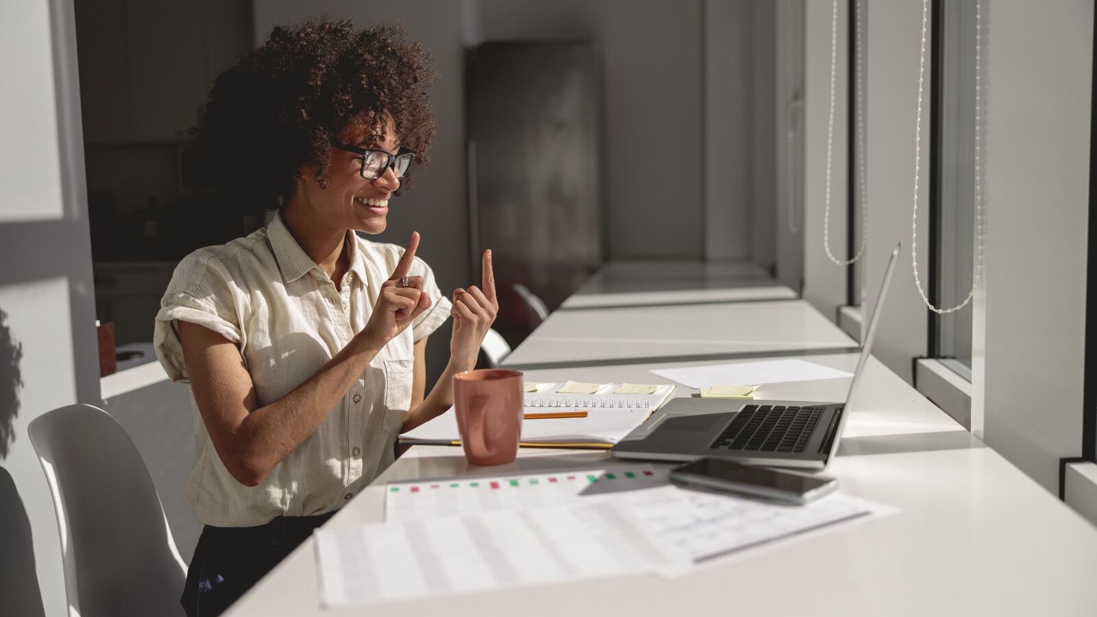 Una mujer se comunica a través de señas por televideo en un ambiente laboral.