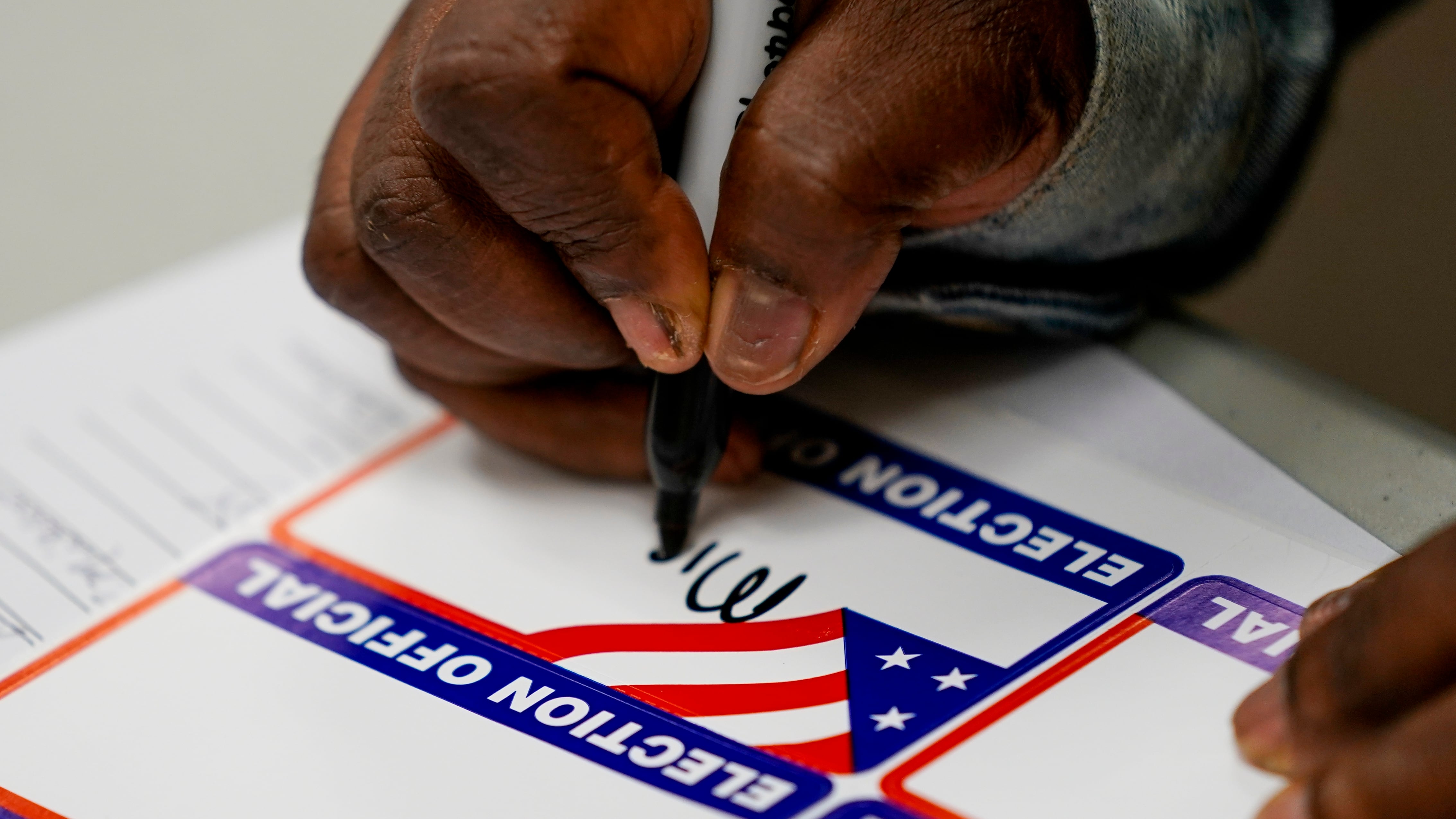 Un trabajador electoral firma durante una clase para trabajadores electorales de Milwaukee el sábado 22 de octubre de 2022, en Milwaukee. (AP Photo/Morry Gash)