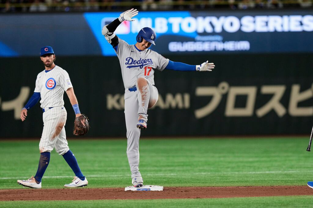Shohei Ohtani, de los Dodgers de Los Ángeles (derecha), celebra su doblete mientras Dansby Swanson, de los Cachorros de Chicago (izquierda), se para junto a la base en la novena entrada de un juego de la Serie Mundial de Béisbol de la MLB en Tokio, Japón, el martes 18 de marzo de 2025. (Foto AP/Eugene Hoshiko)