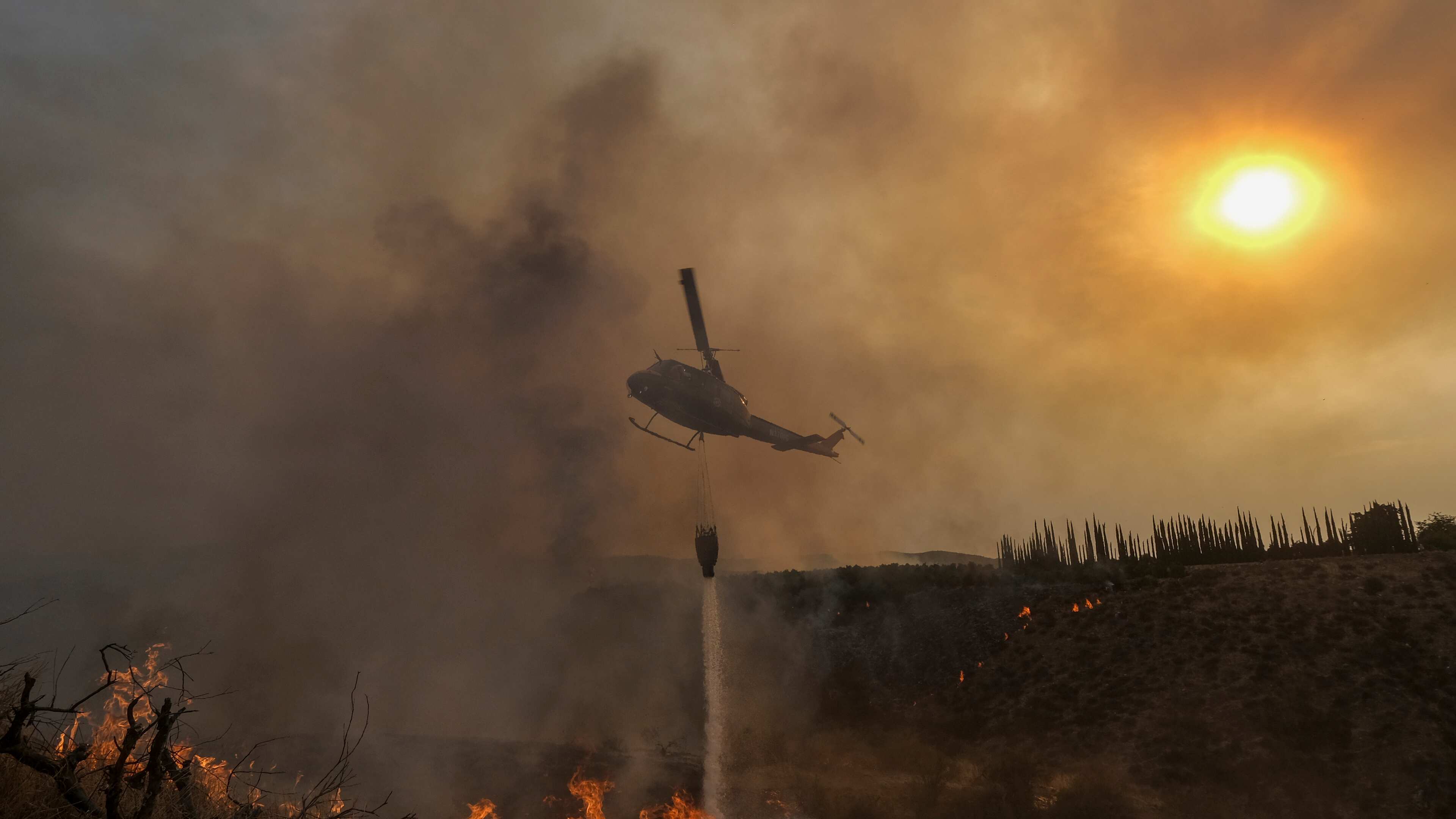 Un helicóptero lanza agua sobre el incendio Fairview en una ladera el jueves 8 de septiembre de 2022, cerca de Hemet, California.
