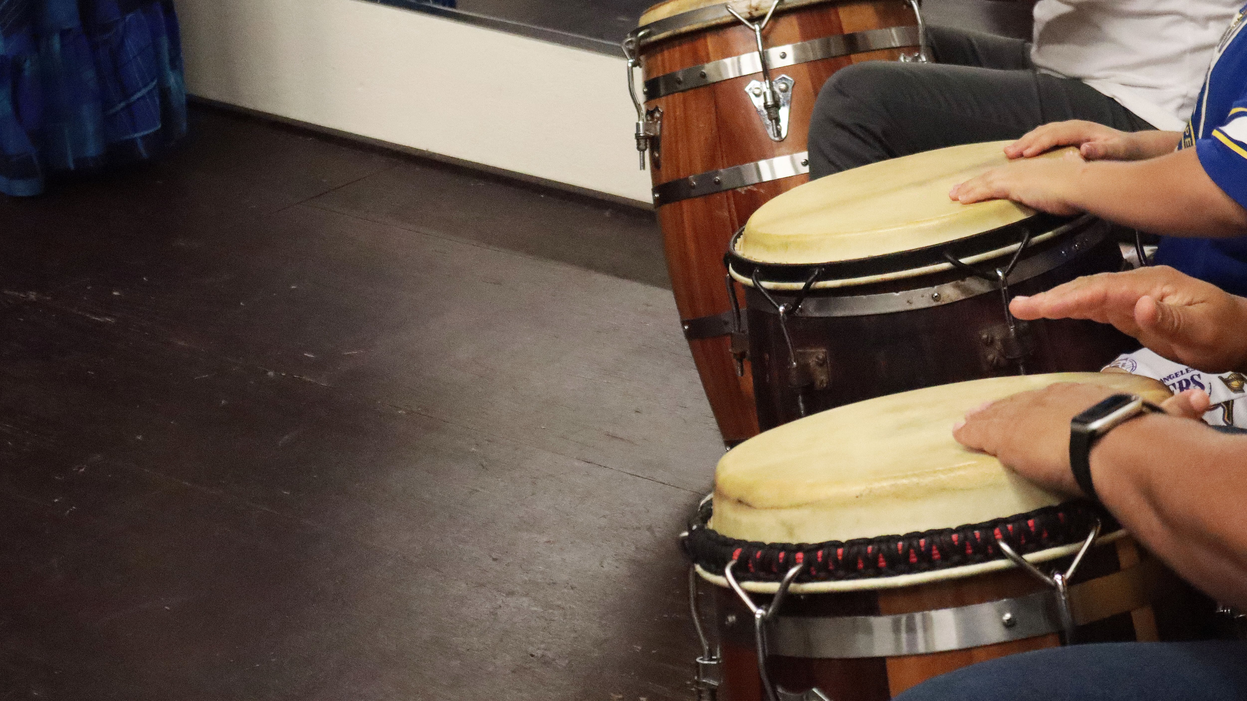 Toma de cerca de los instrumentos de percusion utilizados en la clase basica de bomba y las manos de los musicos que tocaban al ritmo de la bomba.