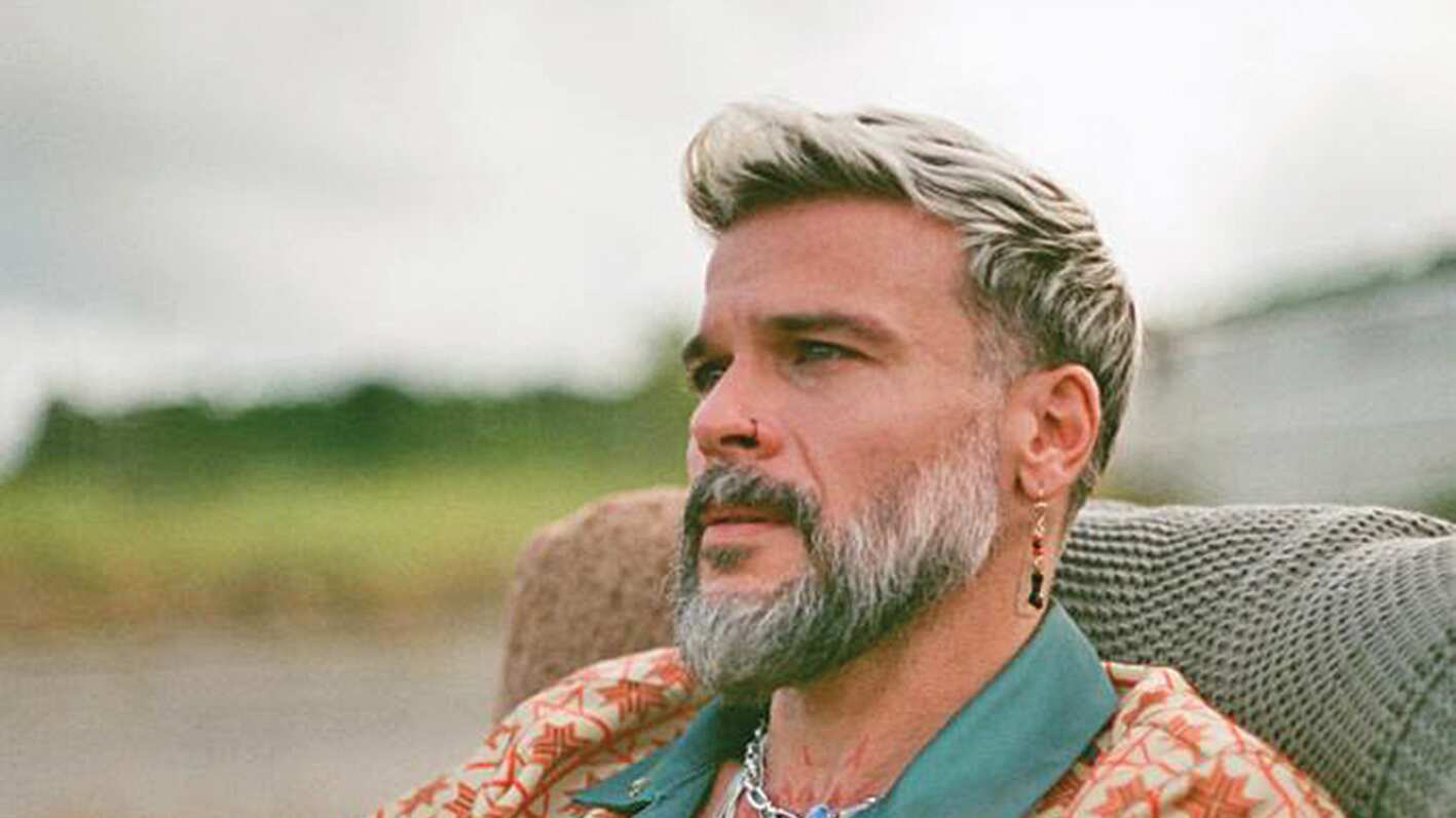 El cantante Pedro Capó aparece sentado, mirando al horizonte.