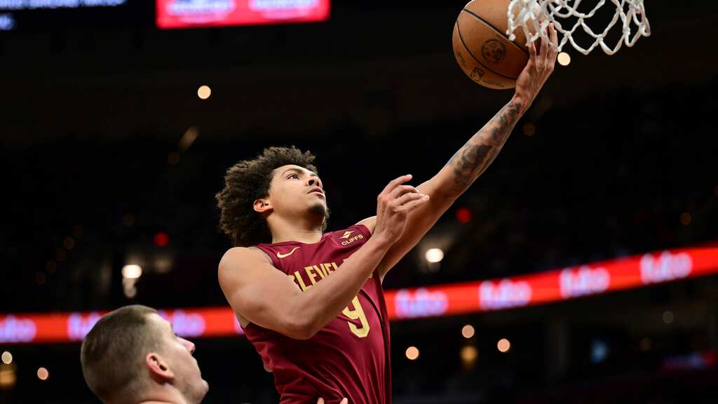 Craig Porter, de los Cavaliers de Cleveland, se alista a encestar contra los Nuggets de Denver, ante la mirada de Nikola Jokic, en la segunda mitad del juego de baloncesto de la   NBA, el domingo 19 de noviembre de 2023, en Cleveland. (AP Foto/David Dermer)