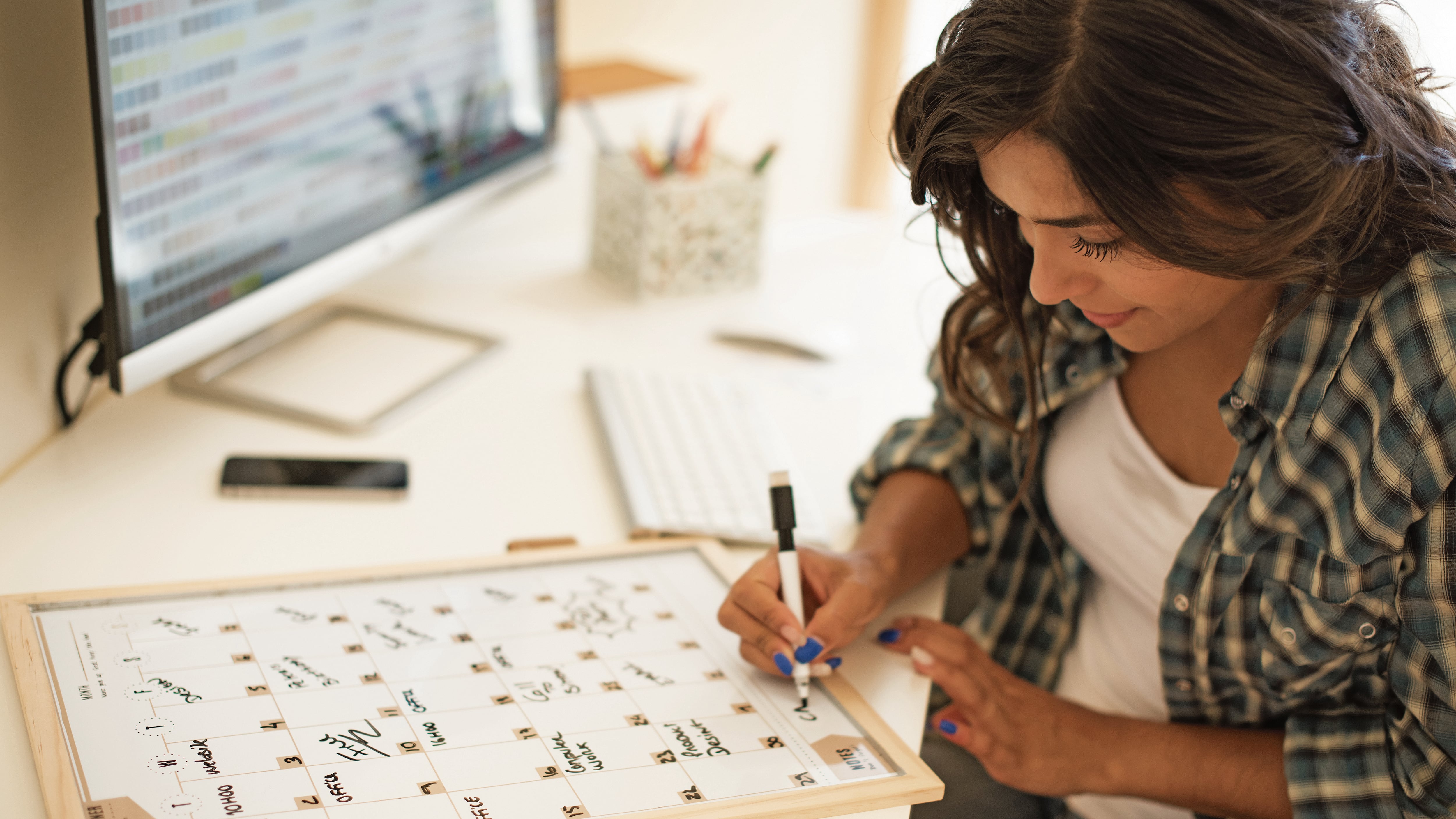 Mujer sentada en escritorio escribiendo en un calendario