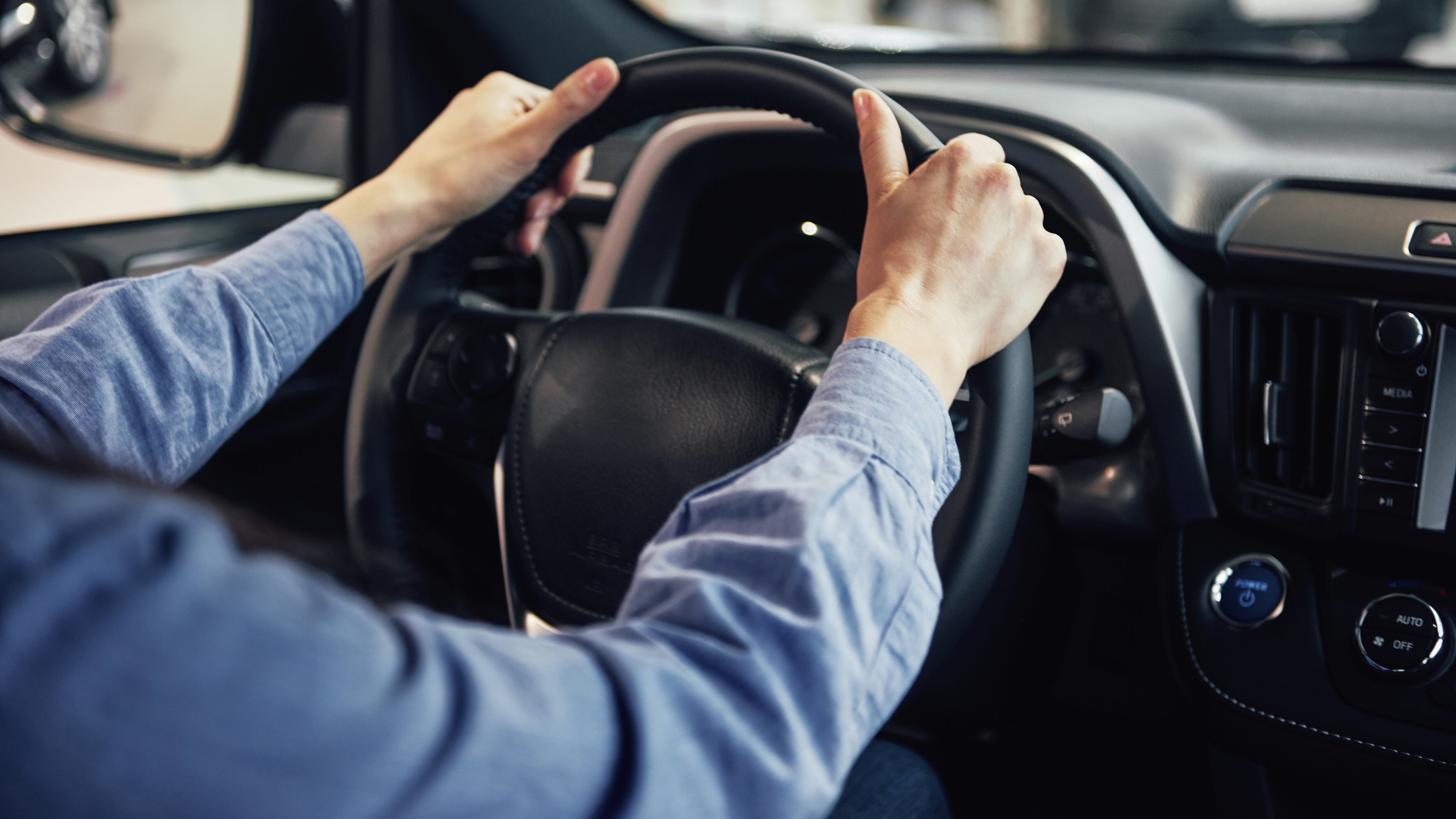 Motorista com mãos no volante.