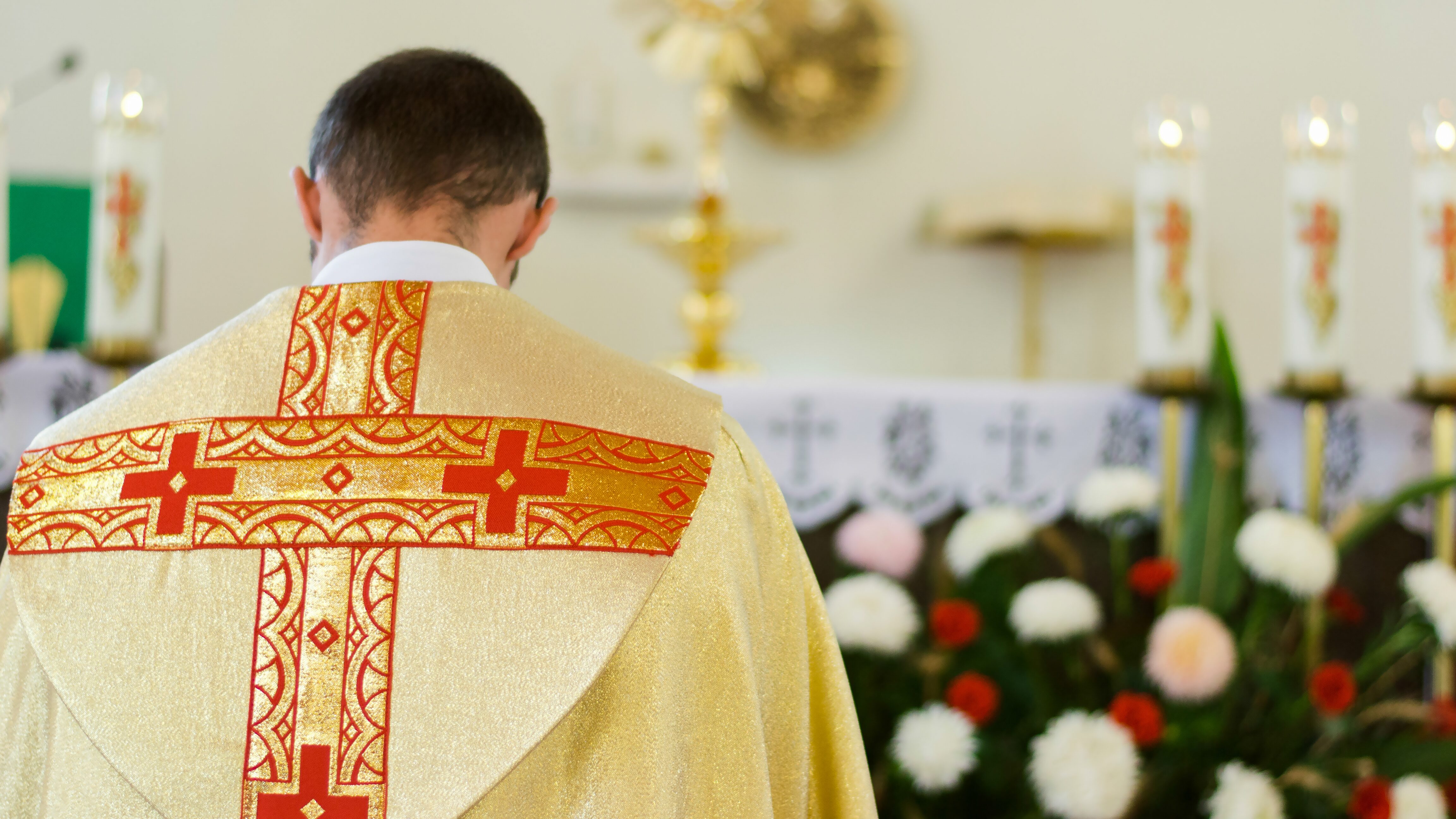 Sacerdote de Iglesia Católica orando frente altar.