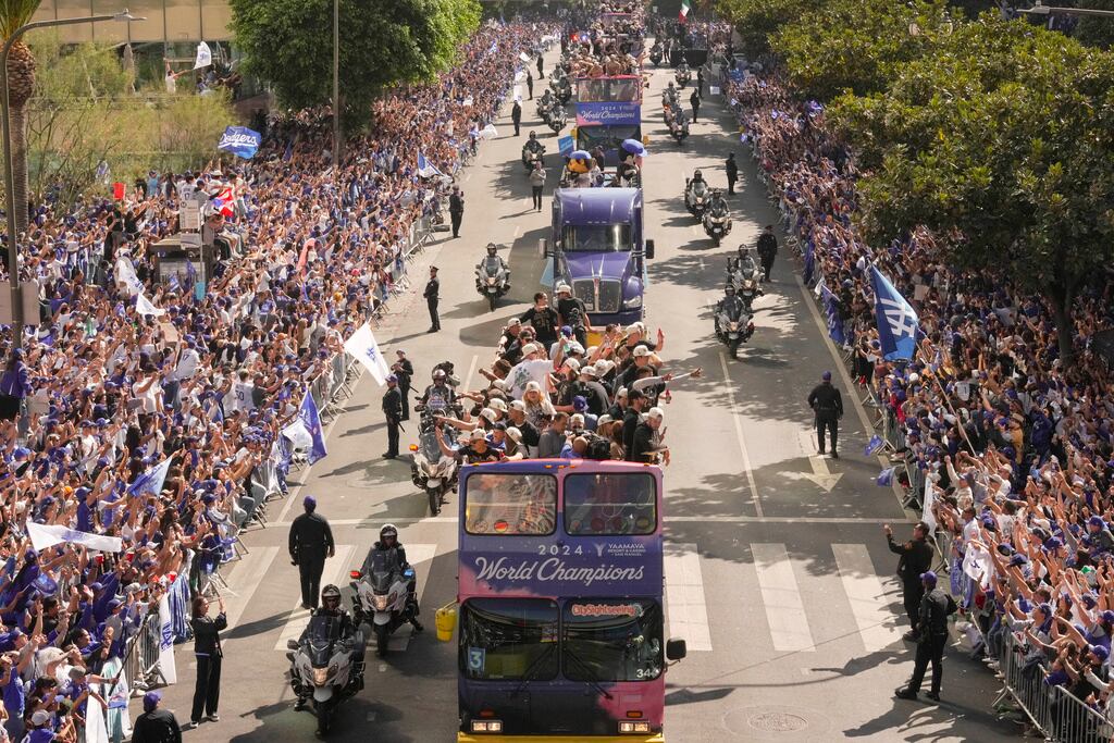Jugadores y equipo de entrenadores de los Dodgers de Los Ángeles se trasladan en autobuses de dos pisos mientras la afición los ovaciona durante el desfile de celebración tras ganar la Serie Mundial. (AP Foto/Damian Dovarganes)