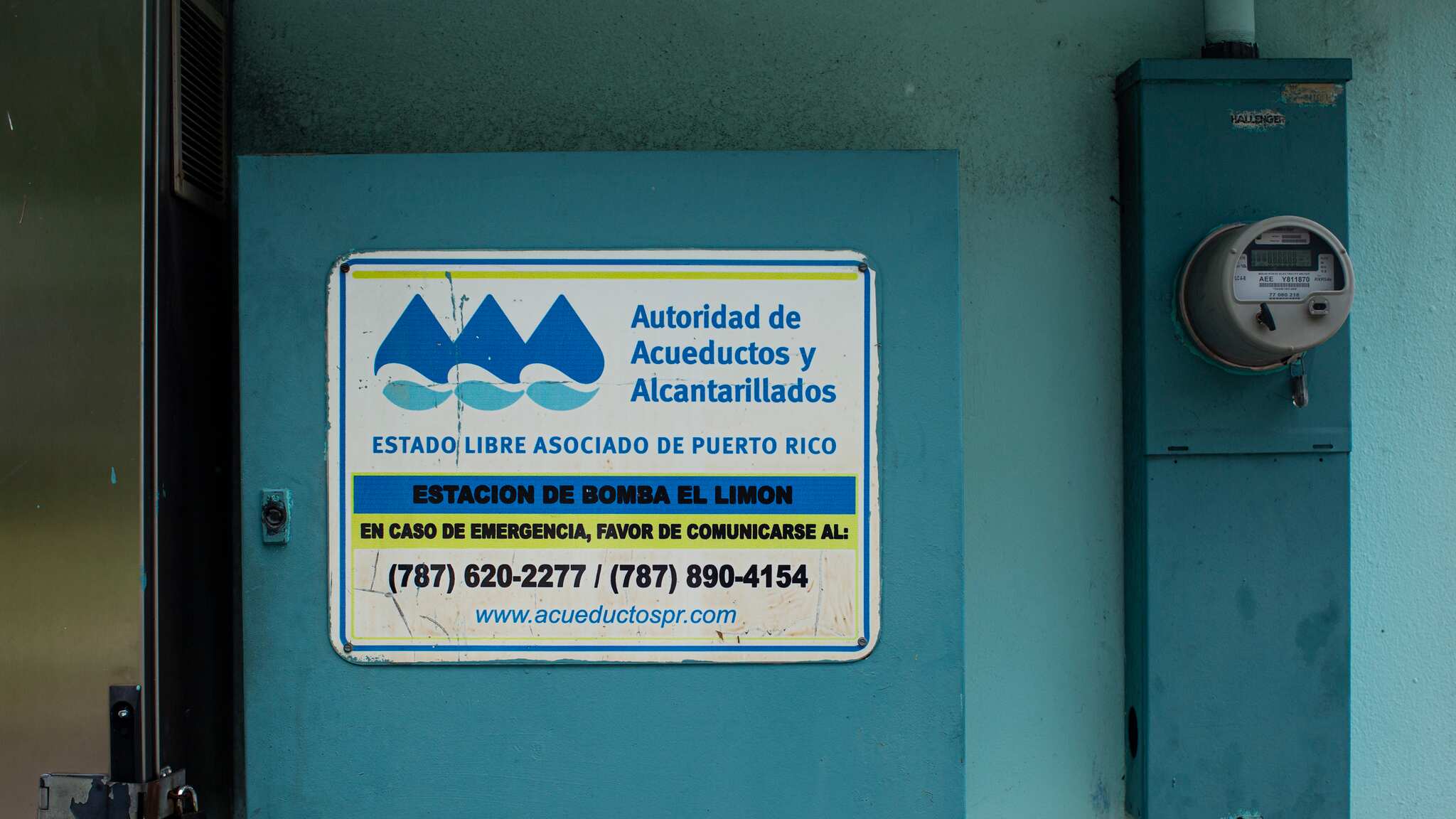 En un cajón color azul, en una pared junto a un contador, tiene un cartel de la Autoridad de Acueductos y Alcantarillados que lee "Estación de bomba El Limón".