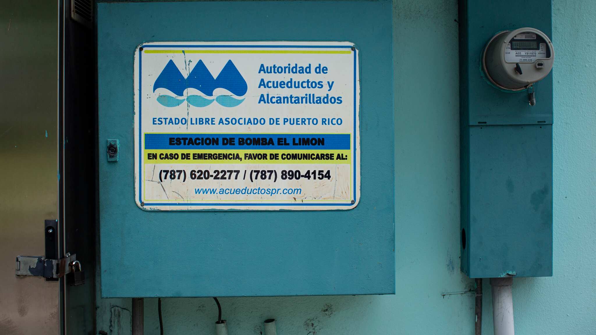En un cajón color azul, en una pared junto a un contador, tiene un cartel de la Autoridad de Acueductos y Alcantarillados que lee "Estación de bomba El Limón".
