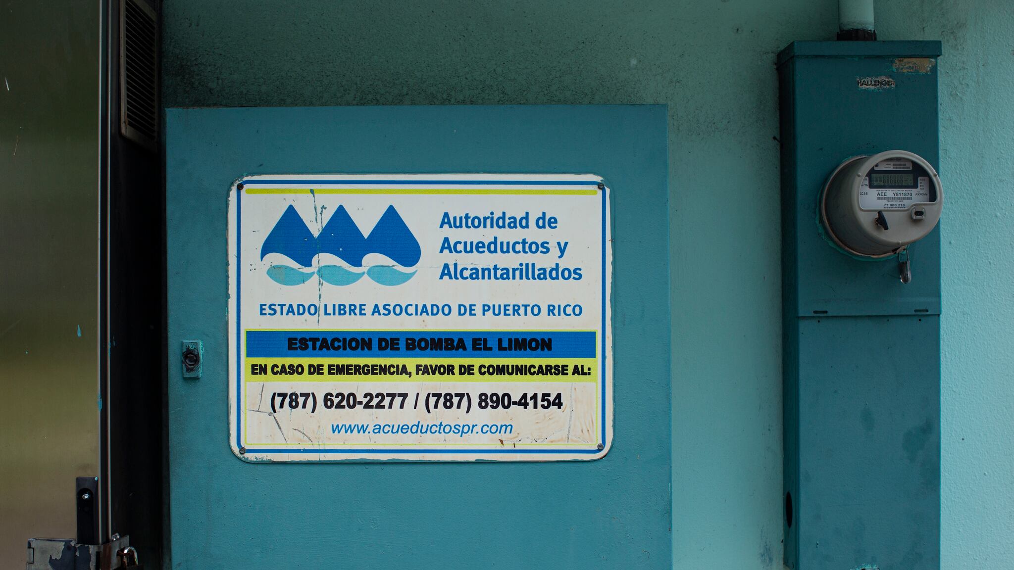 En un cajón color azul, en una pared junto a un contador, tiene un cartel de la Autoridad de Acueductos y Alcantarillados que lee "Estación de bomba El Limón".