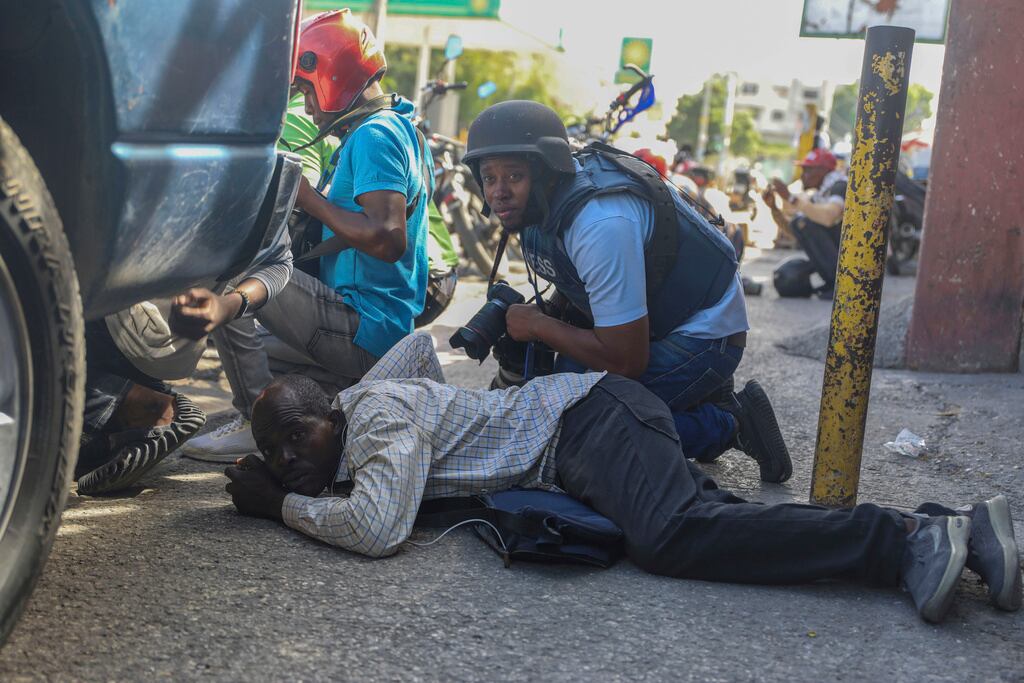 ARCHIVO - Periodistas se protegen del tiroteo entre pandillas y policías en Puerto Príncipe, Haití, el 11 de noviembre de 2024. (Foto AP/Odelyn Joseph, Archivo)