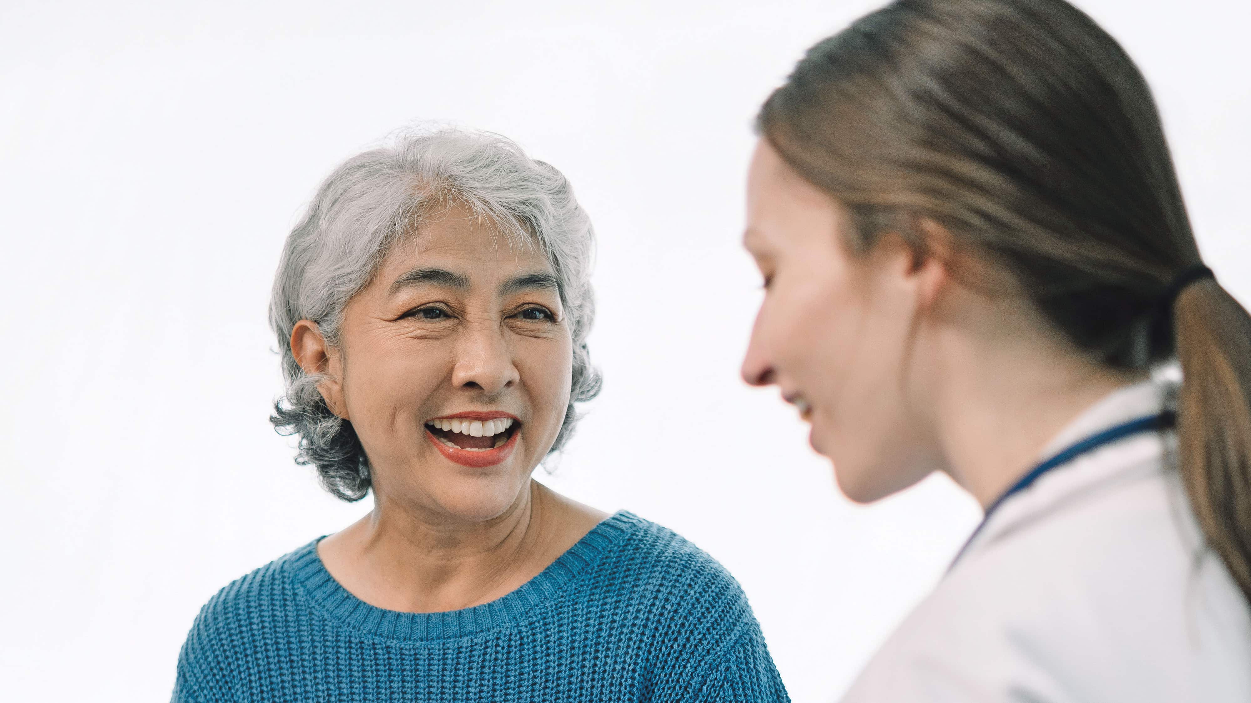 Doctora conversando con una adulta mayor en una consulta.