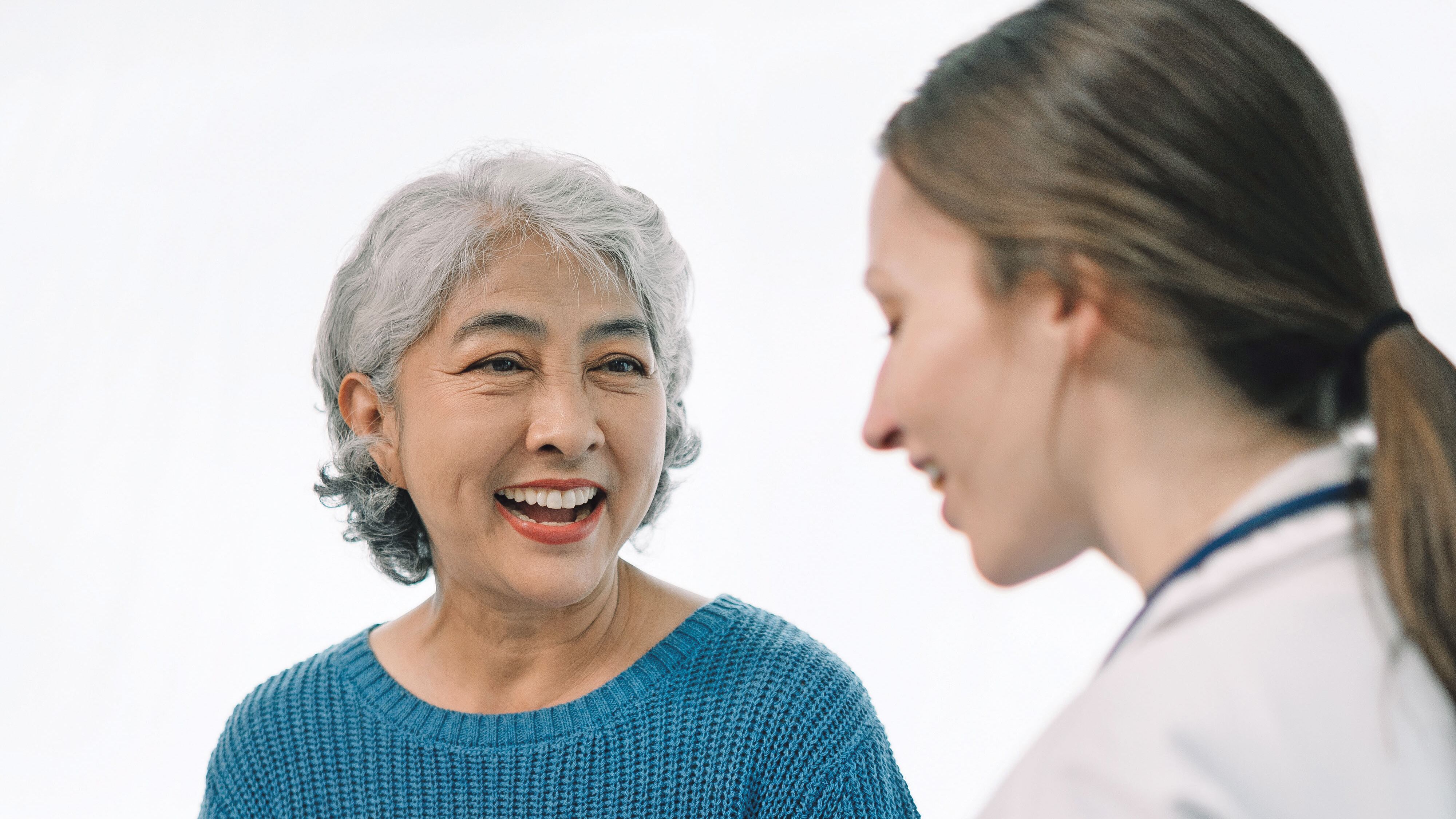 Doctora conversando con una adulta mayor en una consulta.