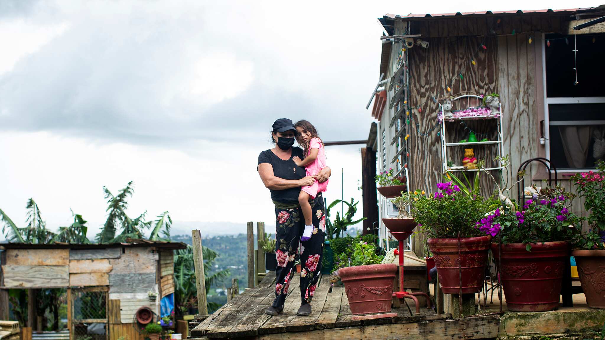 Virgen Báez sostiene a su nieta a las afueras de su hogar.