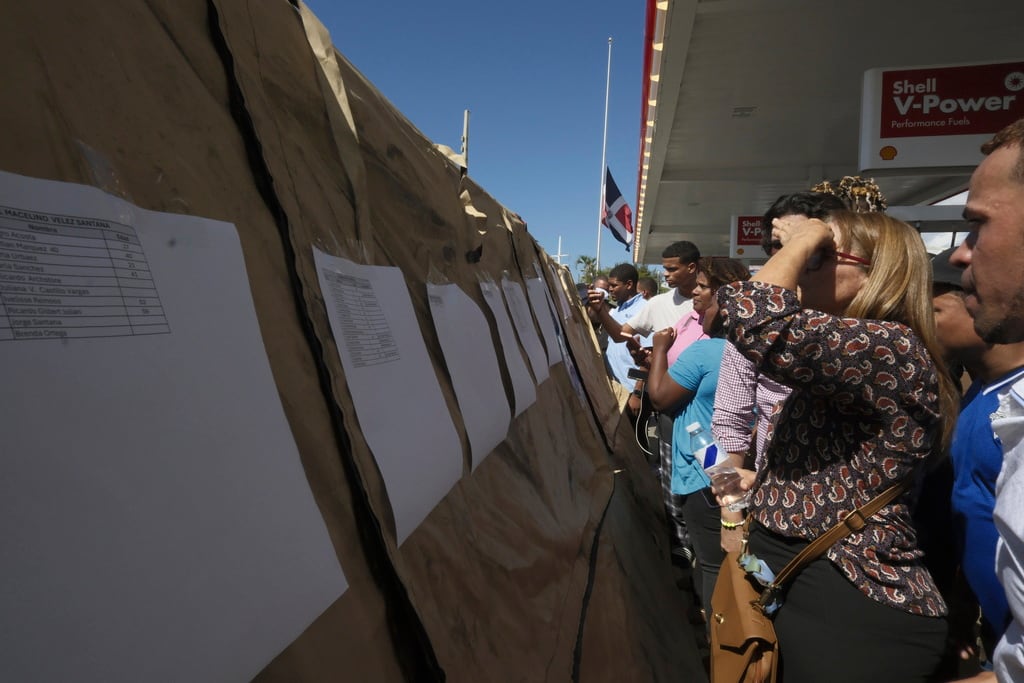 Ciudadanos leen las listas de sobrevivientes mientras los equipos buscan a otros atrapados en el club nocturno Jet Set. (AP Foto/Ricardo Hernández)
