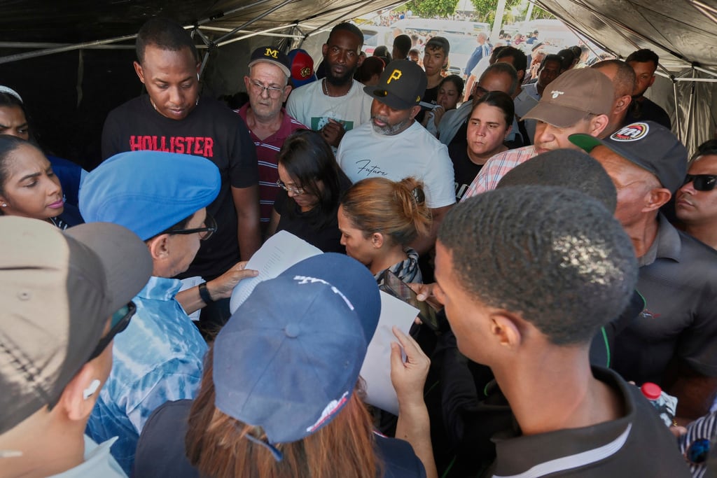 La gente escucha listas de sobrevivientes mientras los equipos buscan a otros atrapados en el club nocturno Jet Set luego de que su techo colapsara durante un concierto de merengue en Santo Domingo. (Foto AP/Ricardo Hernández)