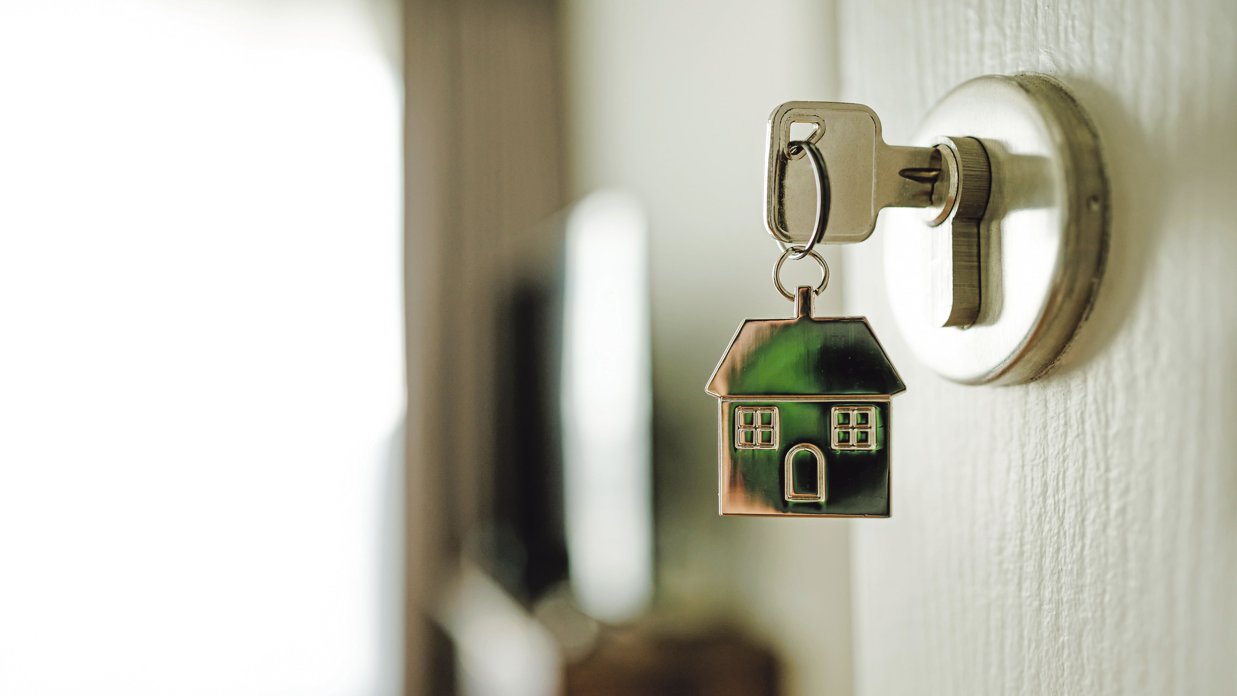 Manija con una llave y un llavero con forma de casa. Inversión inmobiliaria e hipoteca de vivienda.