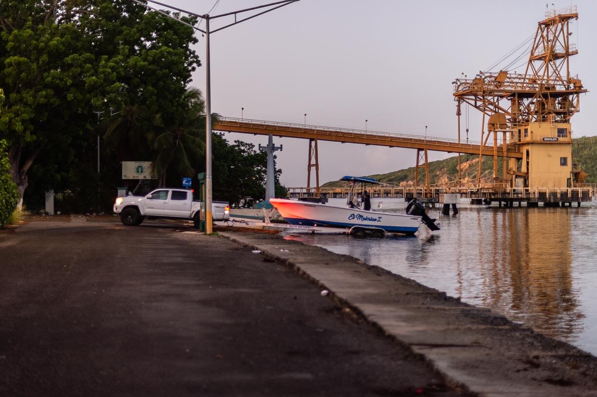 Un pescador tira su lancha para salir a pescar en la madrugada. La rampa que utiliza queda al lado del antiguo muelle, históricamente utilizado por la Ochoa Fertilizer para recibir la materia prima para la fabricación de fertilizantes.
Foto por José Miguel Morales | Centro de Periodismo Investigativo