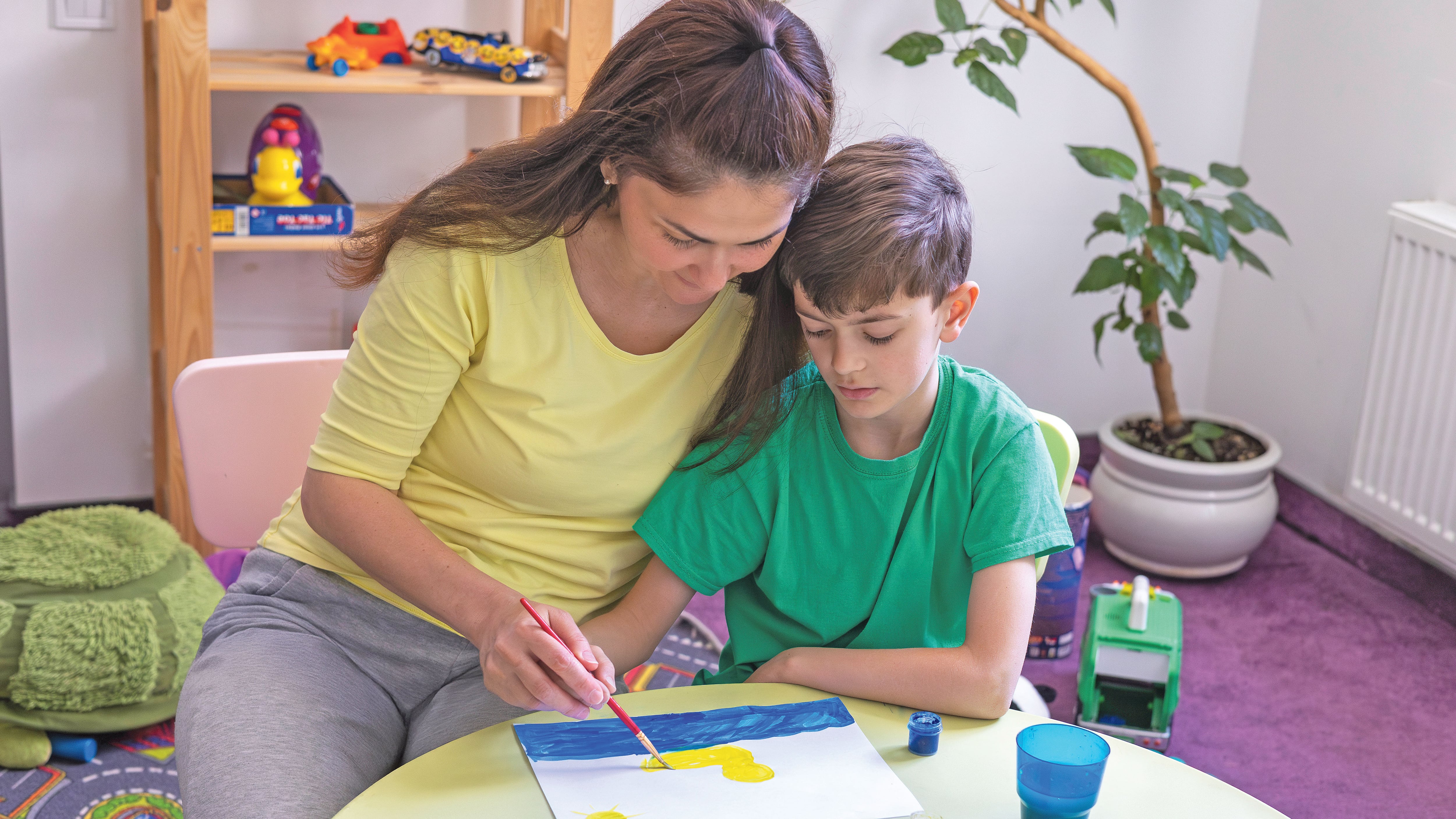 Creatividad, aprendizaje y tiempo en familia. Actividades sensoriales para niños con autismo. Madre e hijo pintando.