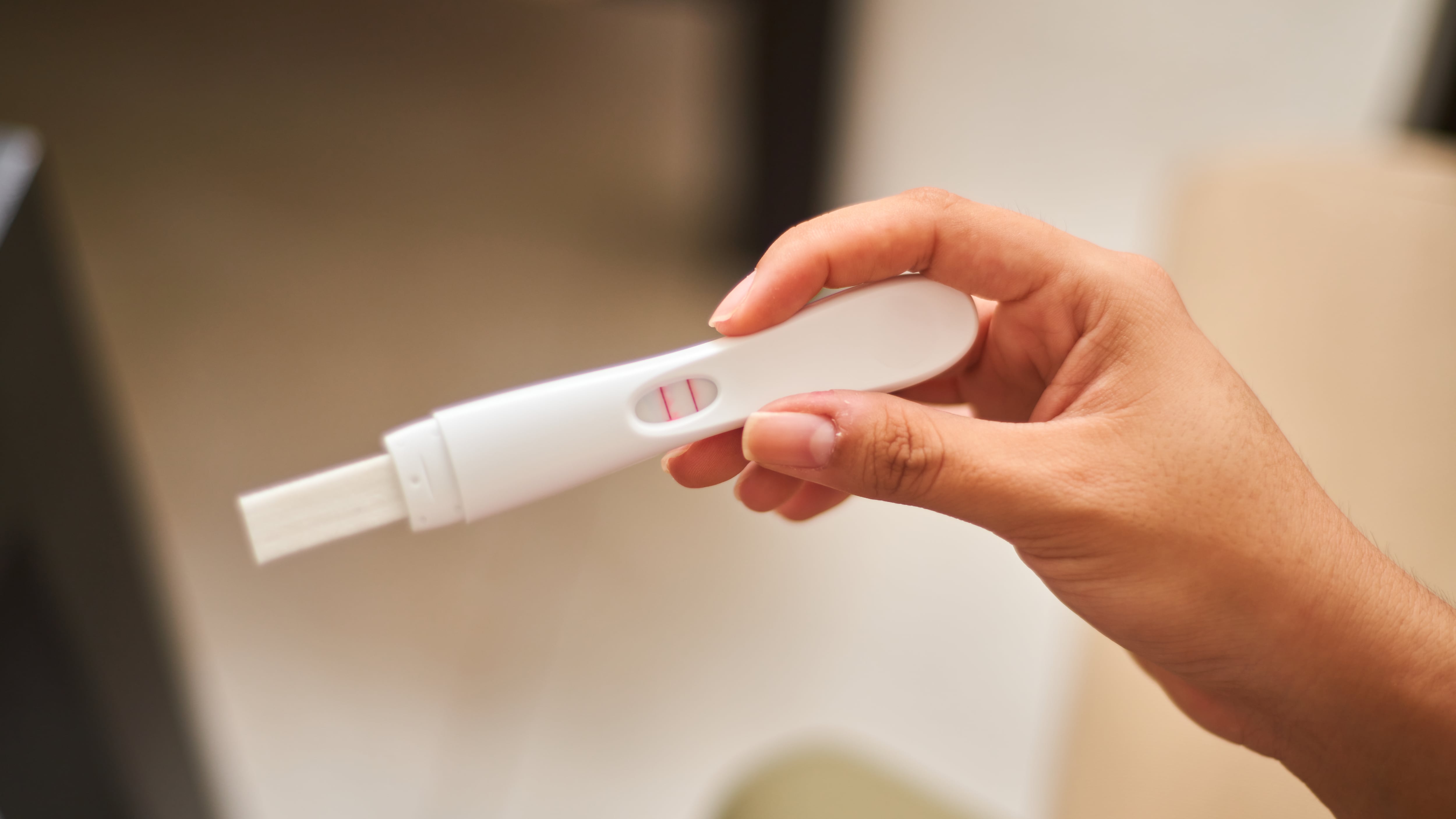 Close up of young latina woman looking at positive pregnancy test. Concept, conscious motherhood, family planning.