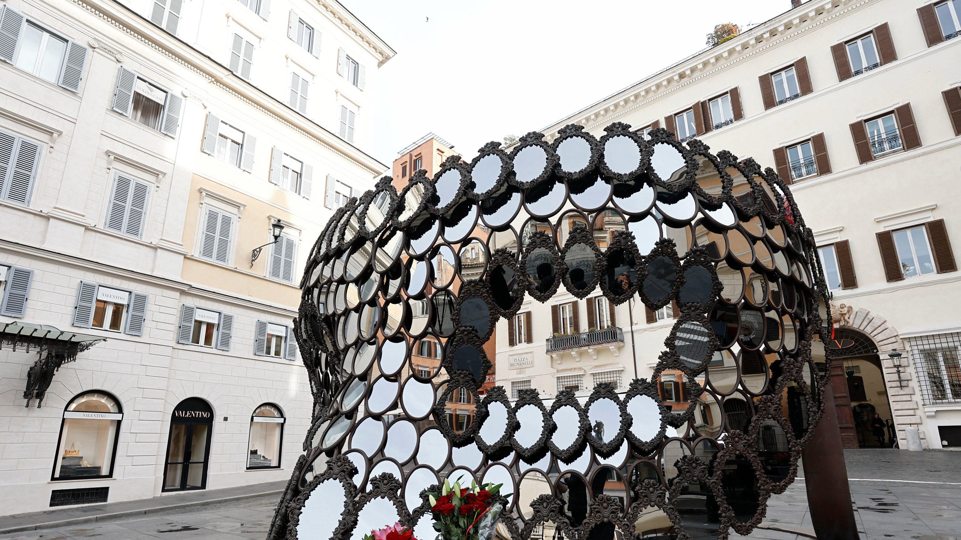 La instalación de máscaras espejo 'Ill Be Your Mirror' de la artista portuguesa Joana Vasconcelos, regalada por la artista a Valentino Garavani, se ve rodeada de ramos de flores en su memoria en la Piazza Mignanelli en Roma, Italia. EFE/EPA/VINCENZO LIVIERI