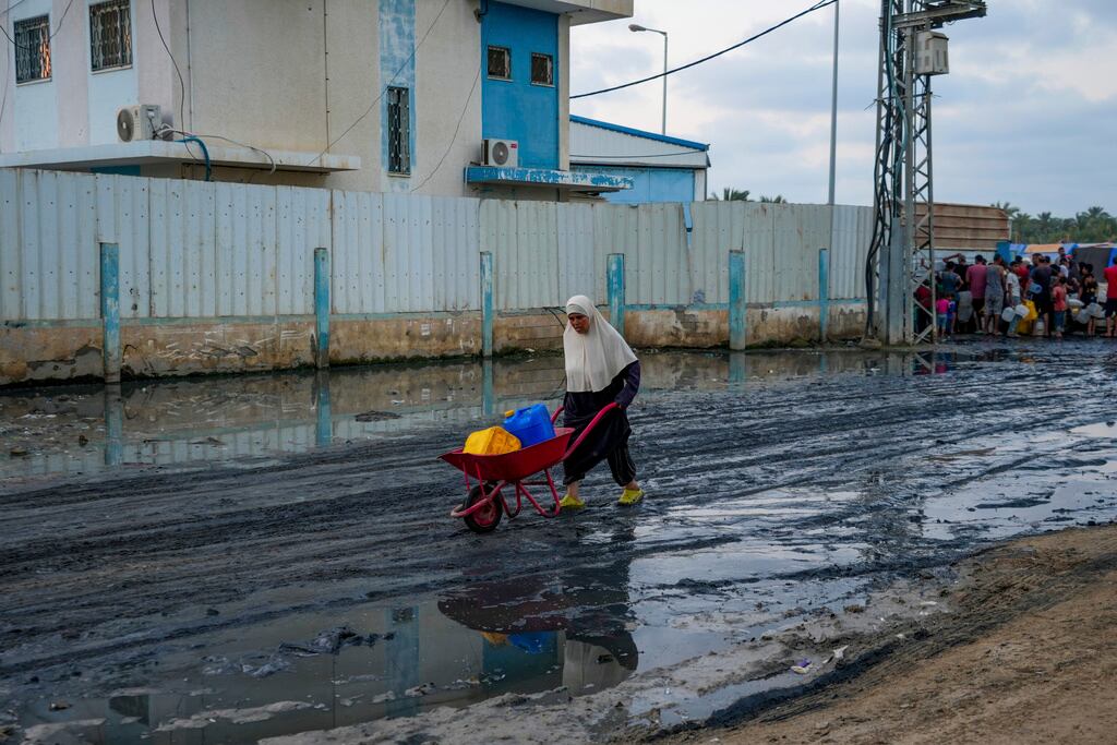 Una mujer empuja una carretilla para llevar agua.