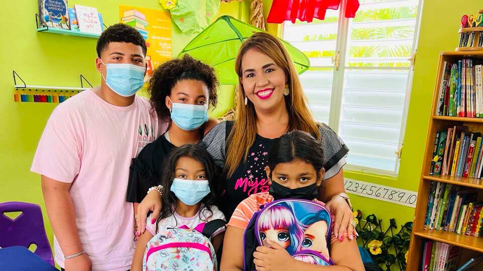 Isaac, Andrea, Janiushka Durán (Fundadora de Mujer Brilla) y dos niñas que recibieron las mochilas con artículos escolares.