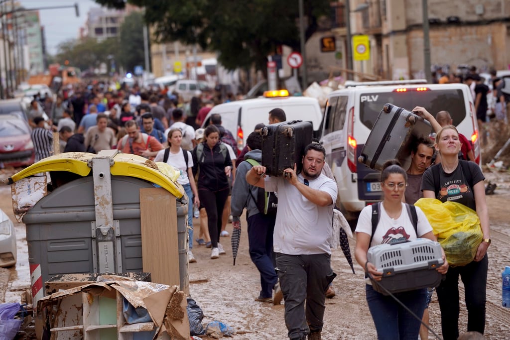 Residentes cargan con sus pertenencias tras abandonar sus viviendas, afectadas por las inundaciones en Valencia, España, el jueves. (AP Foto/Alberto Sáiz)