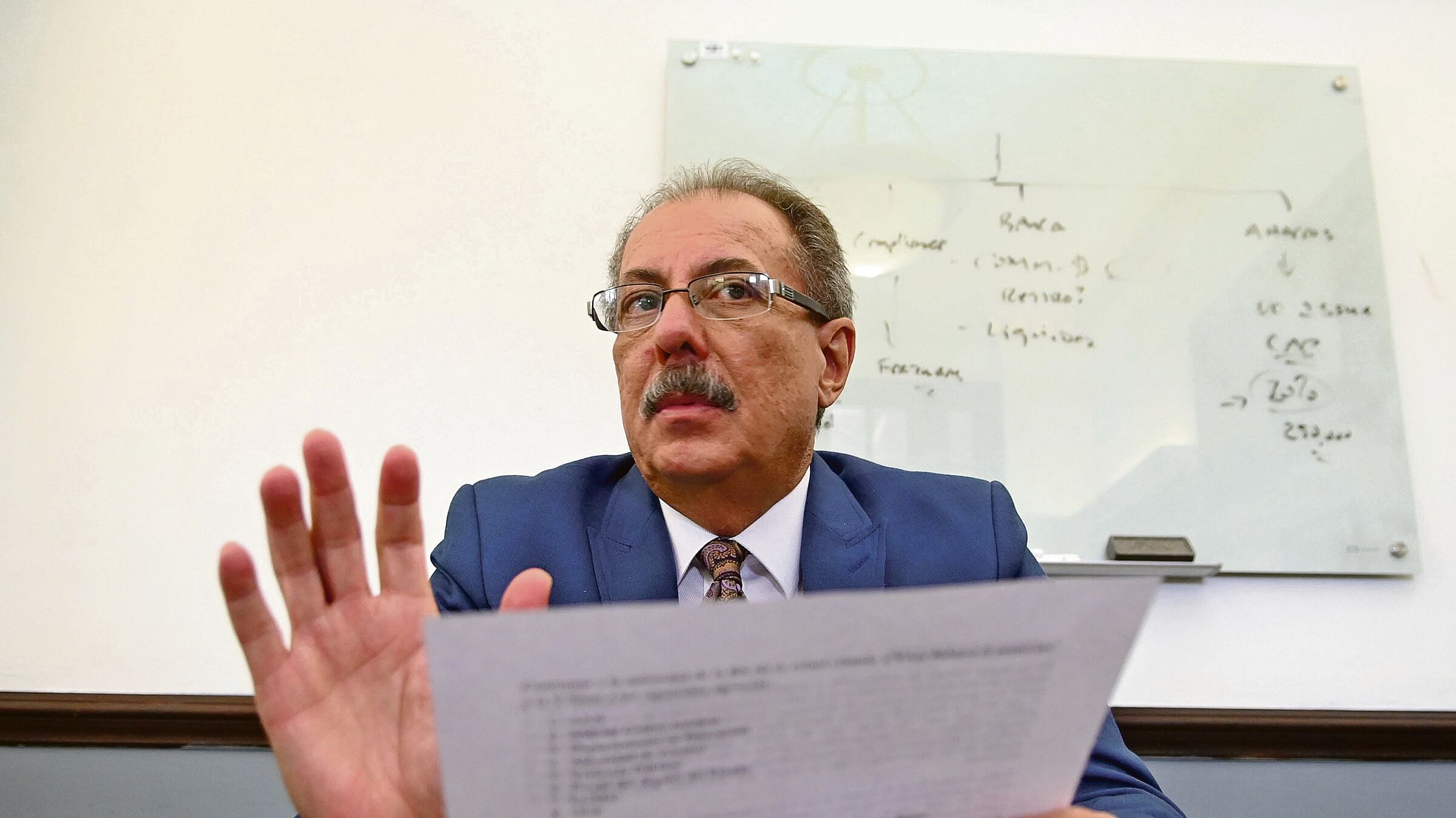 El senador Juan Zaragoza aparece sosteniendo un papel con una mano y levantando la otra.