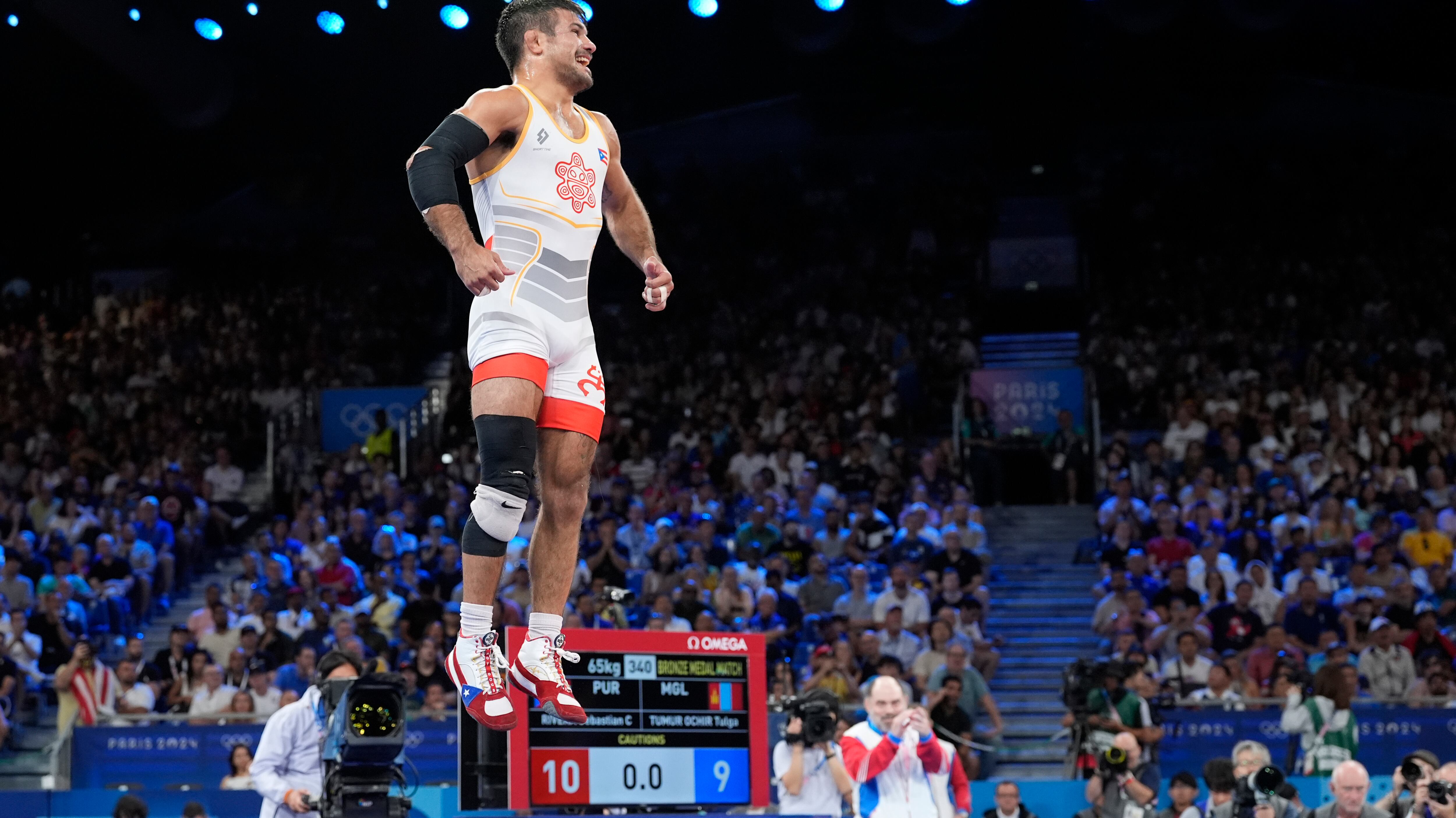 El puertorriqueño Sebastián Rivera celebra después de derrotar a Tumur Ochir Tulga de Mongolia en su combate por la medalla de bronce en la categoría libre masculina de 65 kg en la Arena Champ-de-Mars, durante los Juegos Olímpicos de Verano de 2024, el domingo 11 de agosto de 2024, en París, Francia. (Foto AP/Eugene Hoshiko)