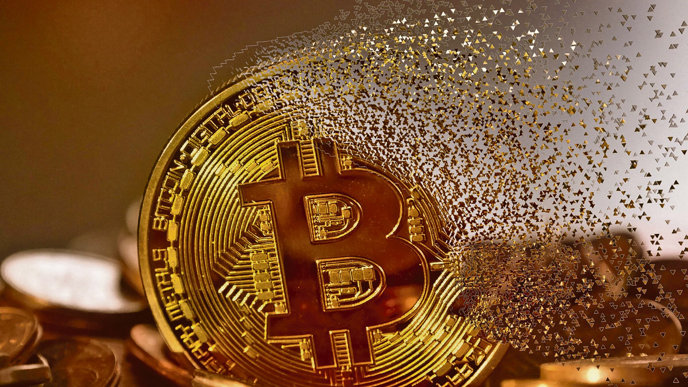 Una moneda con el logo de Bitcoin se descompone en el aire.