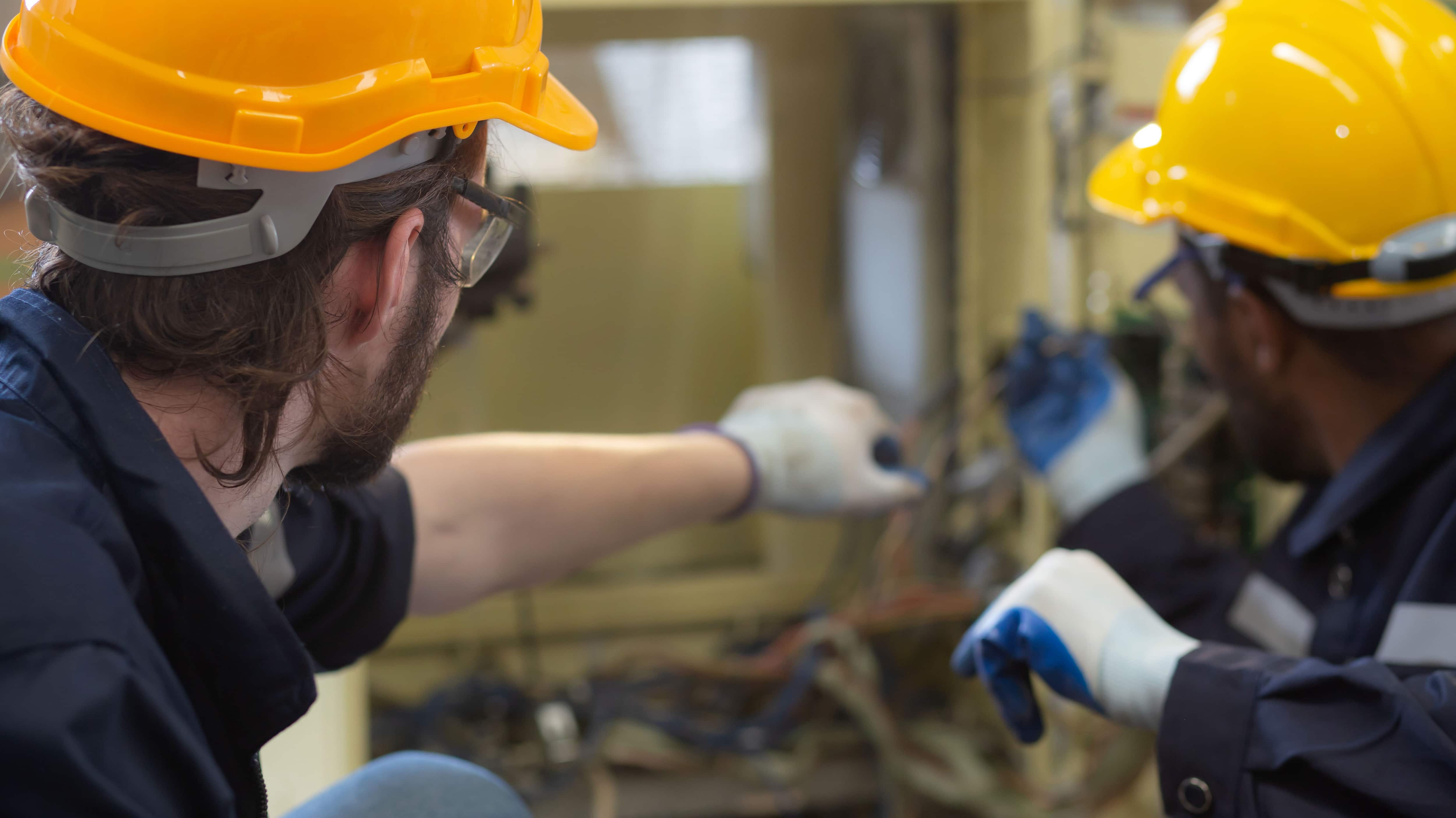 Joven ingeniero realizando mantenimiento y comprobación eléctrica con un profesional en una fábrica, electricista reparando y solucionando problemas con experiencia, solucionando problemas de voltaje e inspeccionando.