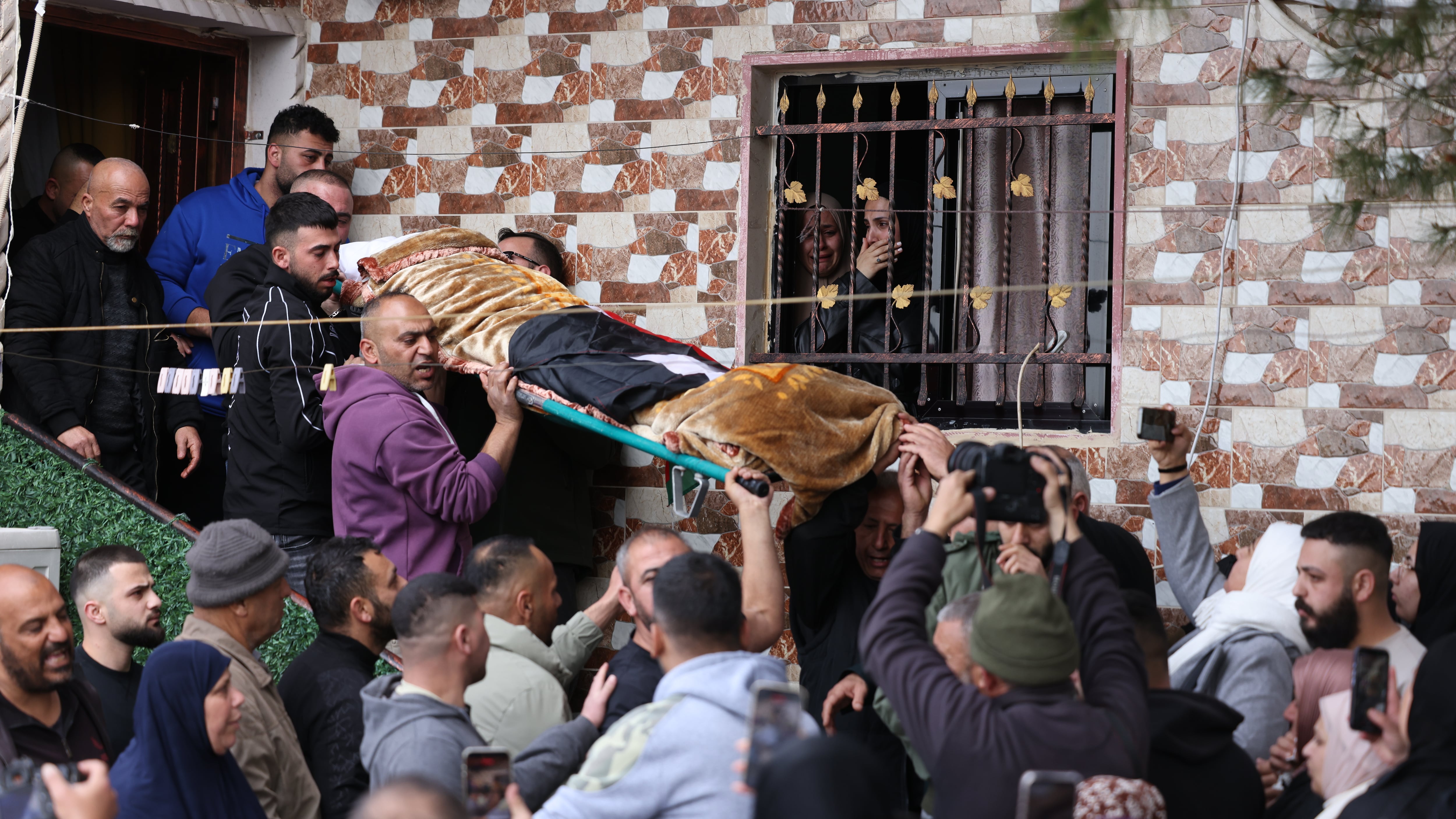 Funeral de tres de las cuatro mujeres que murieron el miércoles por la noche en la aldea de Beit Awa, en Cisjordania, por un impacto de un misil de racimo iraní, alcanzadas cuando estaban en una caseta prefabricada que servía de salón de belleza femenino. Son las primeras víctimas de misiles iraníes en el territorio palestino, donde la población -excepto los colonos israelíes- no cuenta con refugios antiaéreos, a diferencia del territorio israelí. EFE/EPA/ALAA BADARNEH