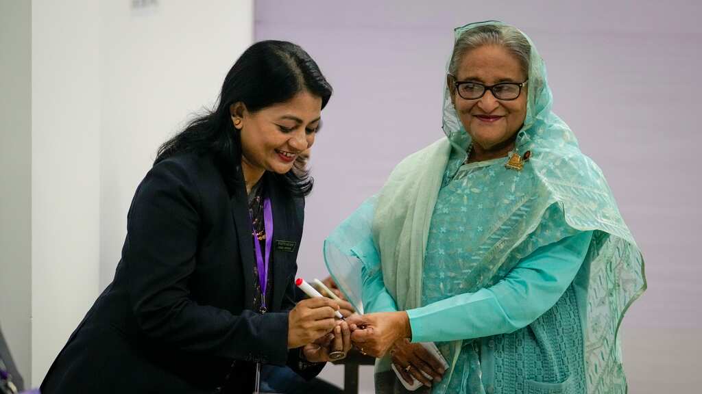 Una policía de Bangladesh pone tinta indeleble en el dedo de la primera ministra del país, Sheikh Hasina, a su llegada para votar en Daca, Banfladesh, el domingo 7 de enero de 2024. (AP Foto/Altaf Qadri)