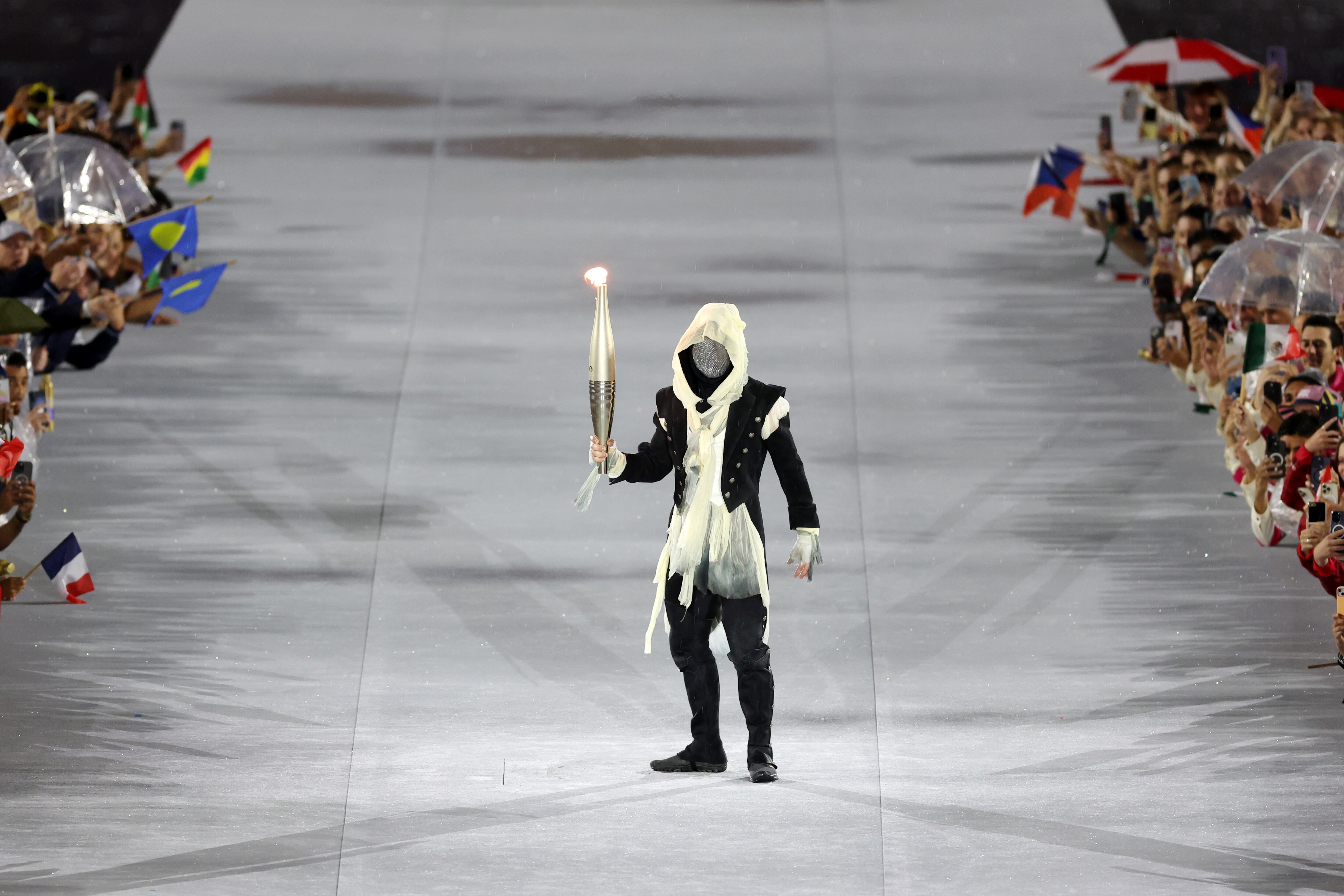 PARIS, FRANCE - JULY 26: Mysterious Torchbearer holds the Olympic Torch during the opening ceremony of the Olympic Games Paris 2024 on July 26, 2024 in Paris, France. (Photo by Jamie Squire/Getty Images)