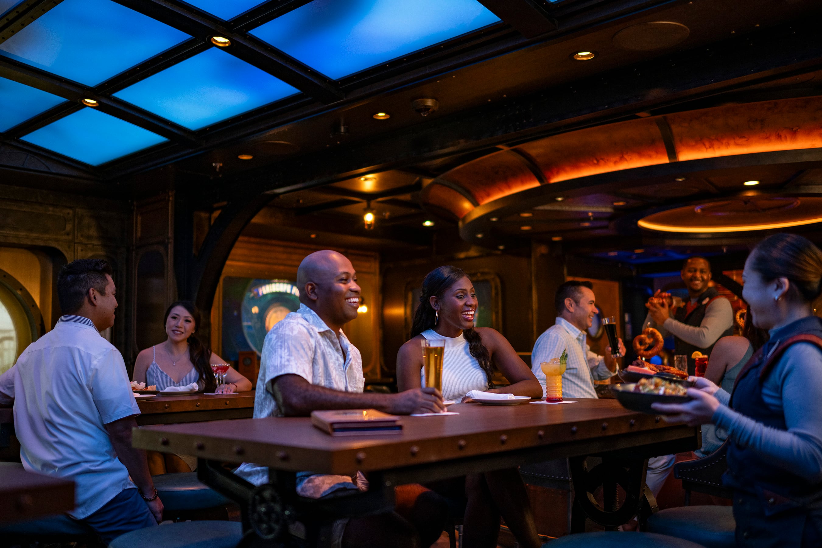 On board the Disney Treasure, Disney Cruise Line’s newest ship, guests dive into the mythical depths of uncharted oceans at the Periscope Pub. Serving as Disney Cruise Line’s first venue inspired by the spellbinding adventure of Walt Disney’s 1954 film, “20,000 Leagues Under the Sea” and the legacy Disney Parks attraction, the submarine-styled interiors give guests a look at the watery world below through an intriguing glass ceiling. (Matt Stroshane, photographer)