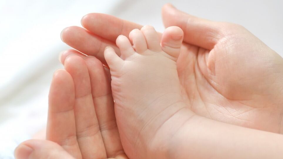 Pies del bebé en manos de la madre.
