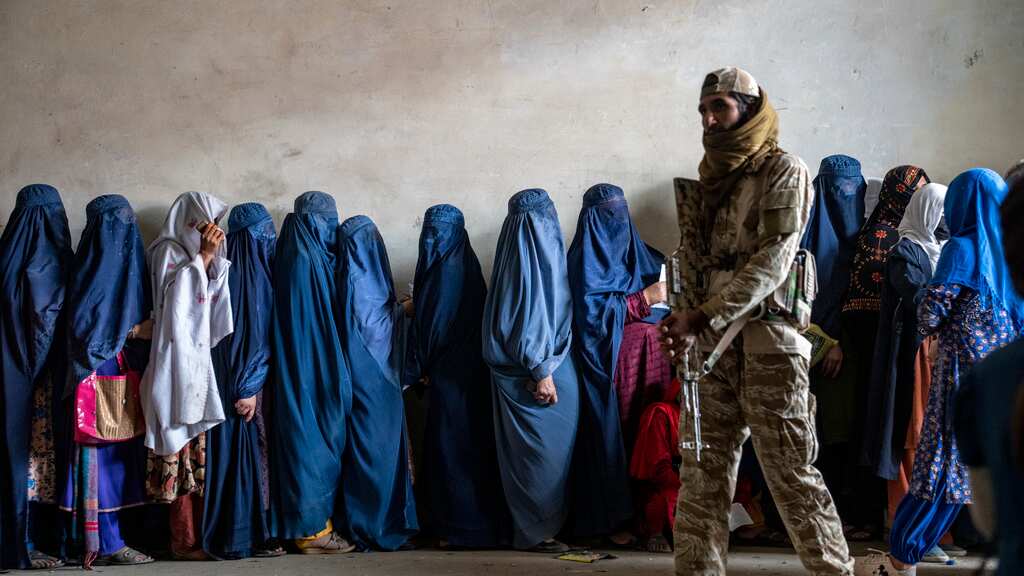 Un combatiente del Talibán monta guardia mientras mujeres esperan a recibir raciones de comida distribuidas por un grupo humanitario, el 23 de mayo de 2023, en Kabul. (AP Foto/Ebrahim Noroozi, Archivo)