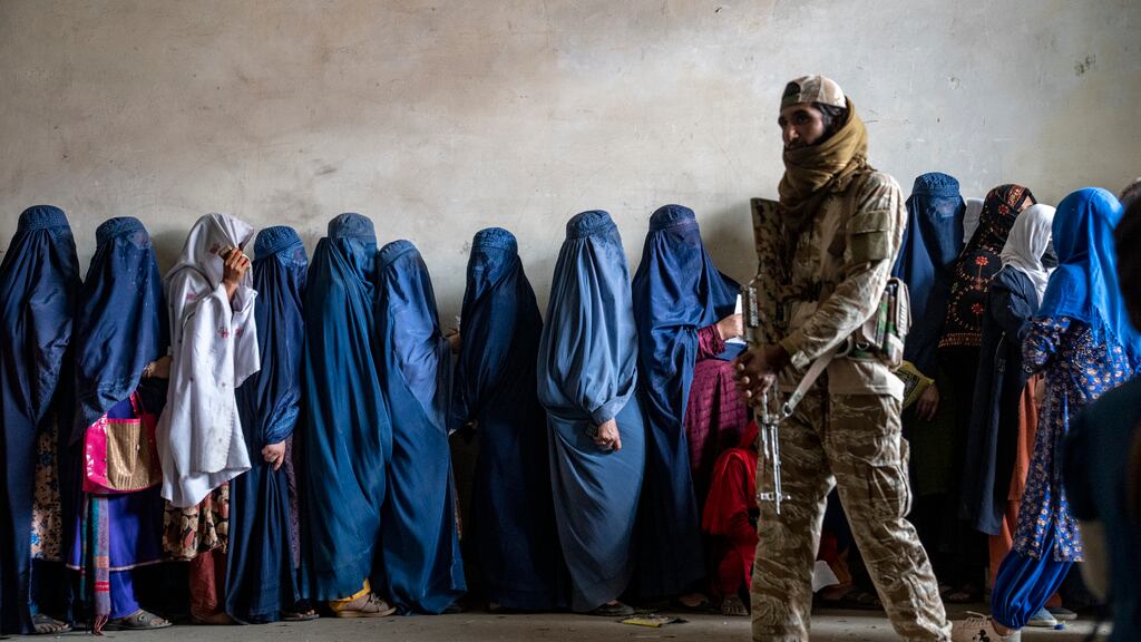 Un combatiente del Talibán monta guardia mientras mujeres esperan a recibir raciones de comida distribuidas por un grupo humanitario, el 23 de mayo de 2023, en Kabul. (AP Foto/Ebrahim Noroozi, Archivo)