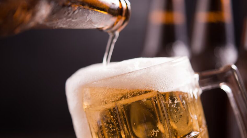 Botellas de vidrio de cerveza con vidrio y hielo sobre fondo oscuro